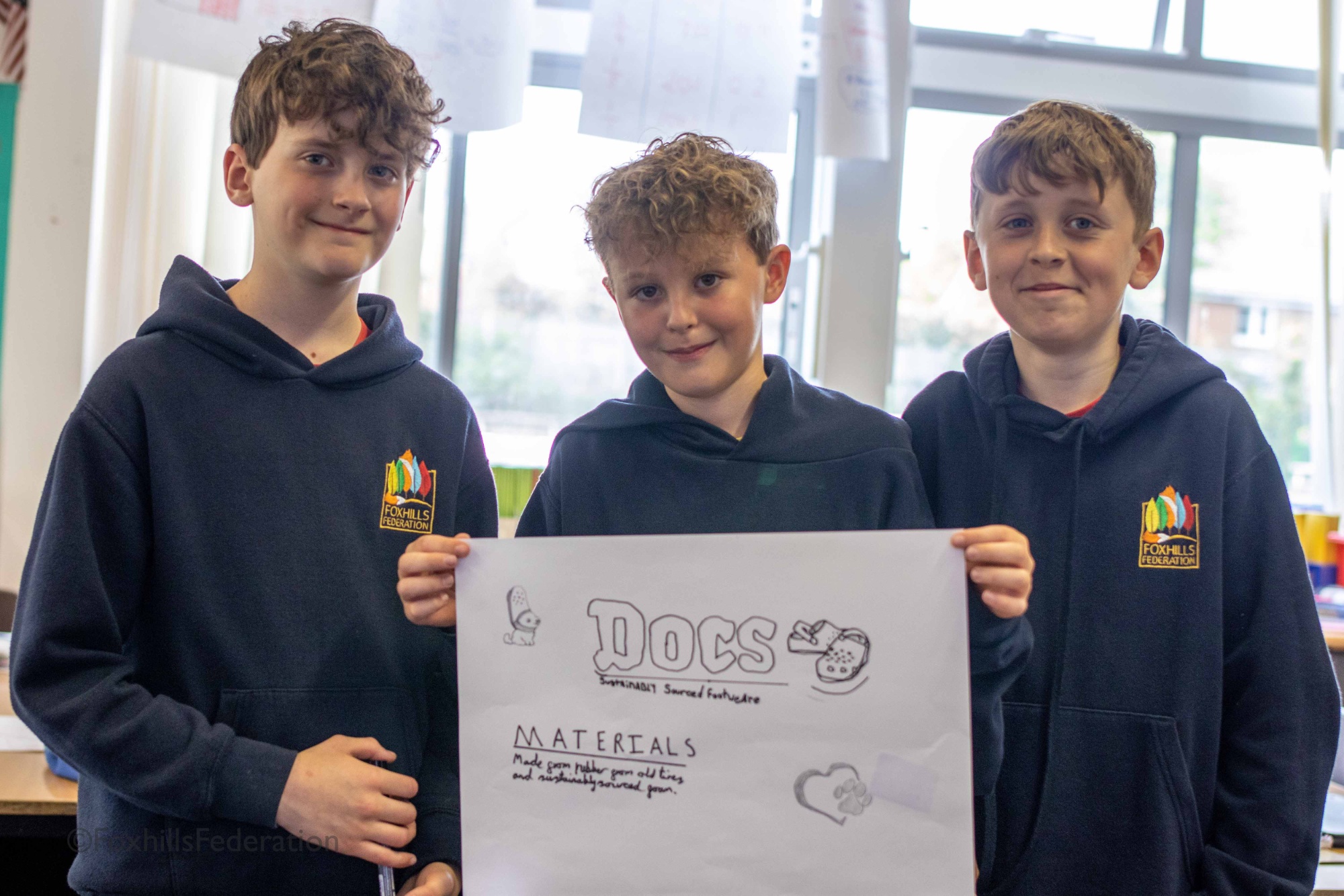 Three children hold up their renewable energy idea