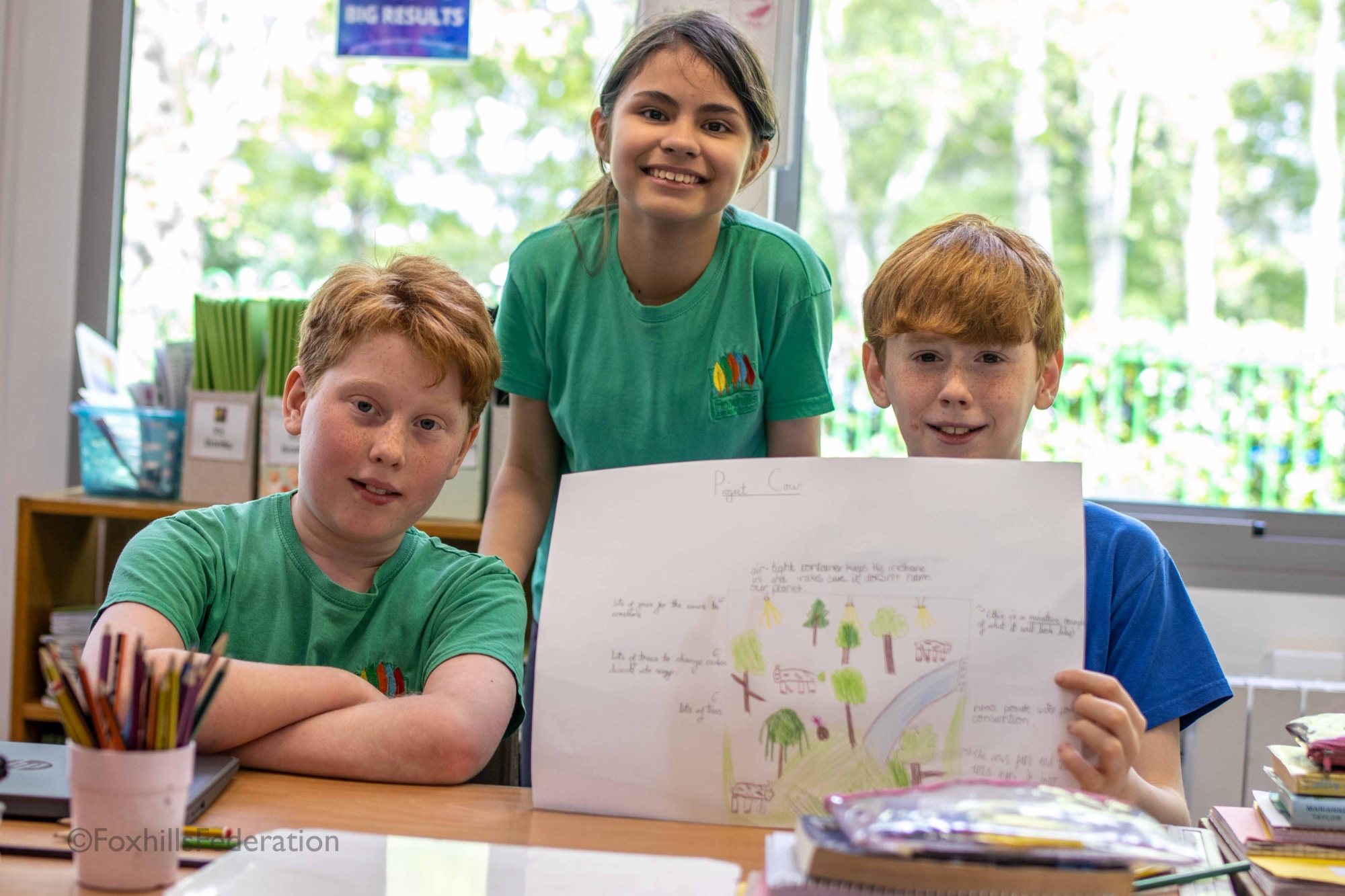 Three children hold up their renewable energy idea