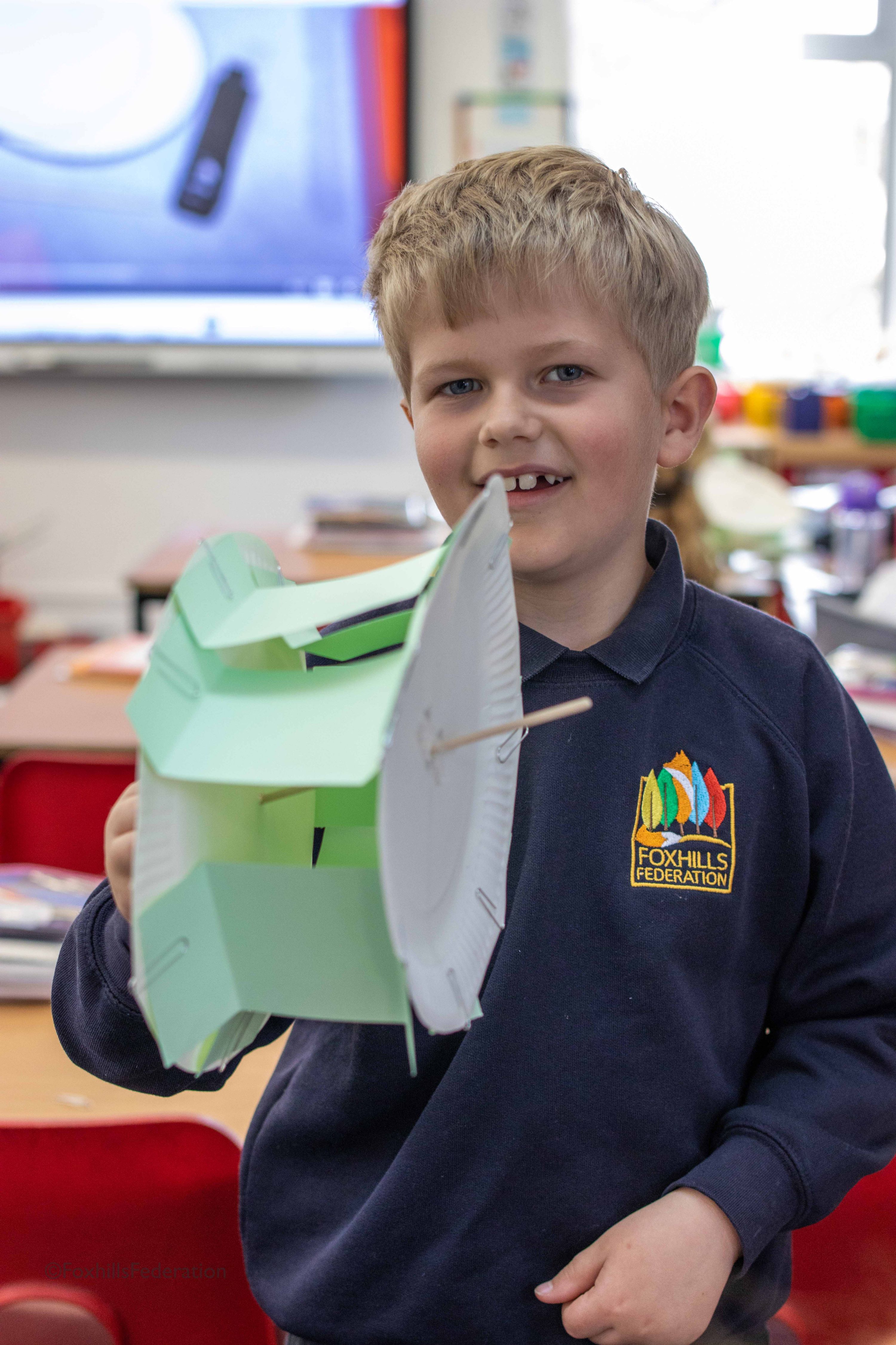 A boy holds up a water wheel