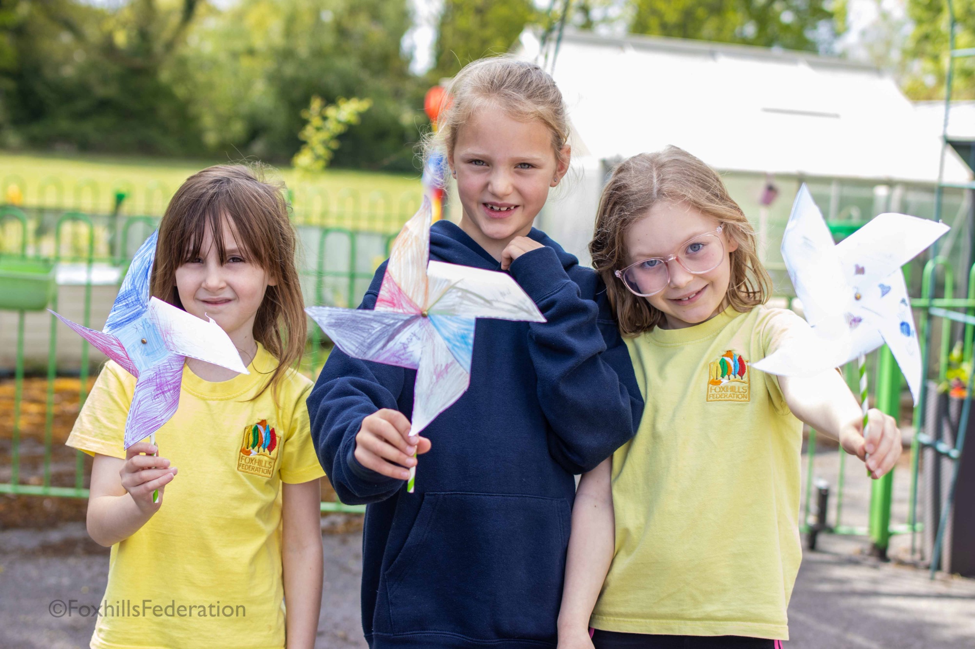 Three girls hold pinwheels