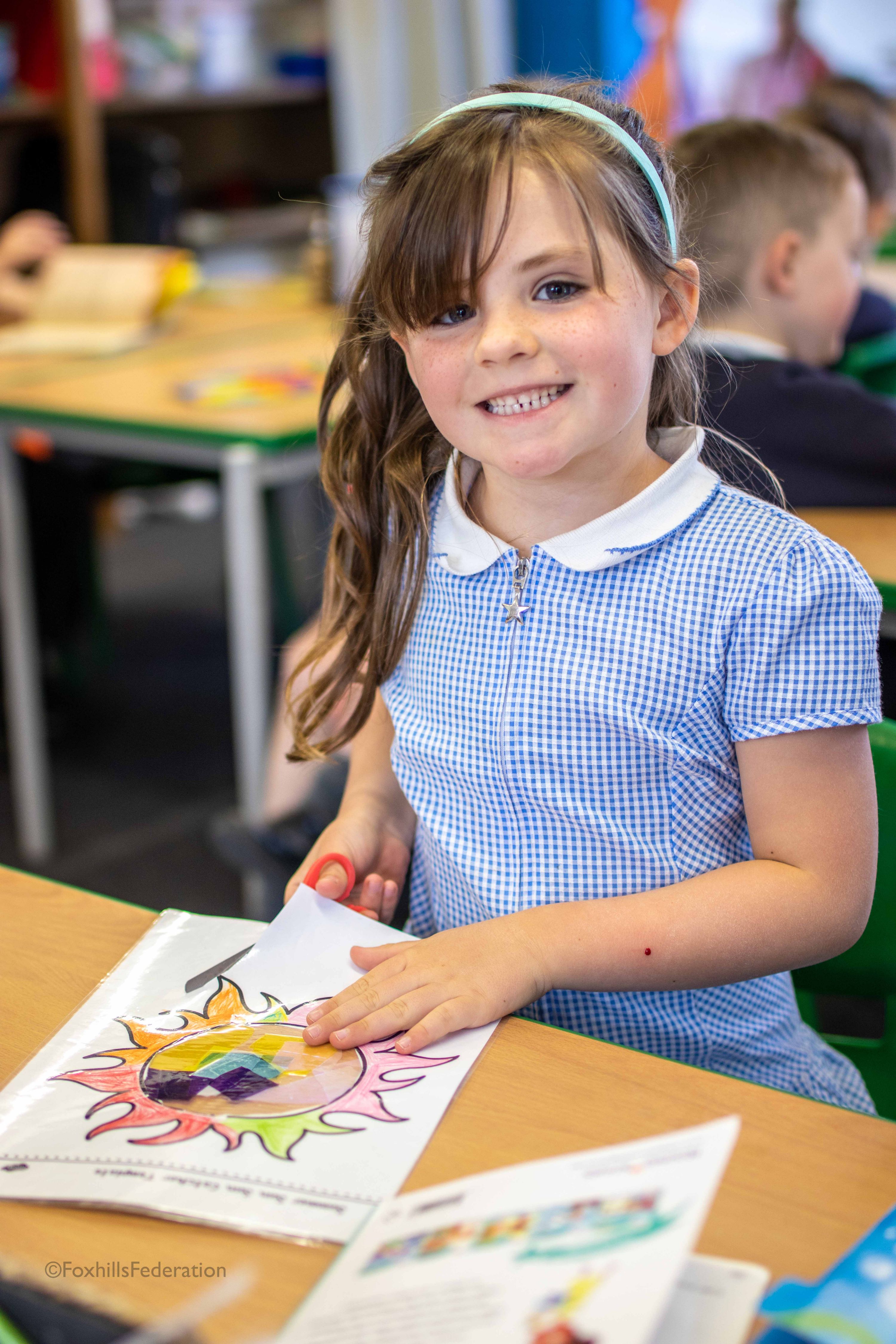 A girl smiles while cutting out colourful foil