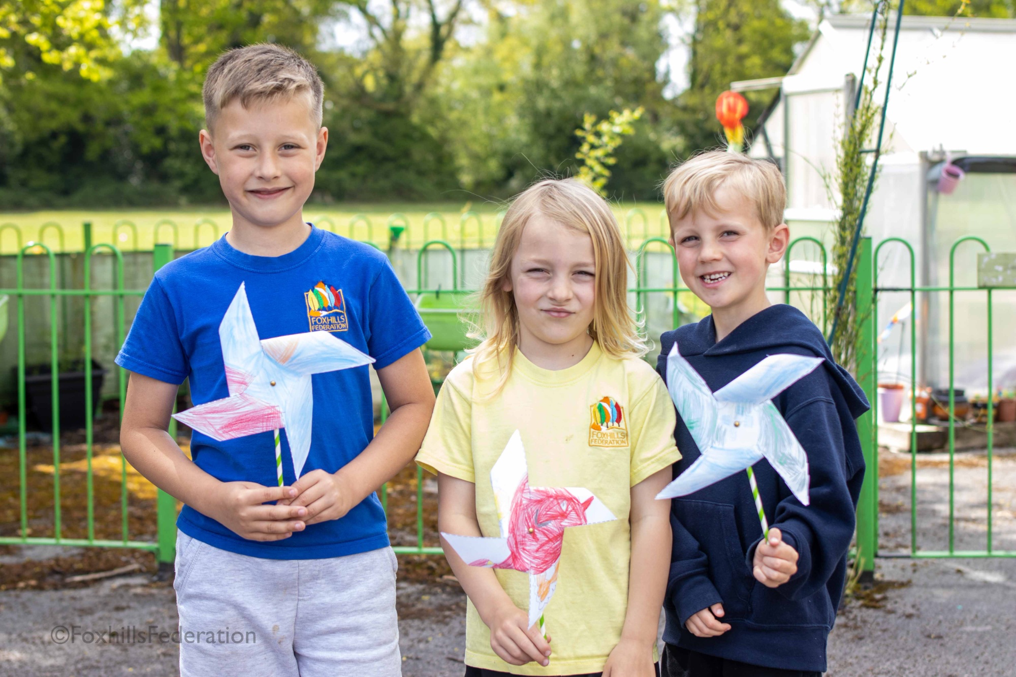 Three boys hold pinwheels