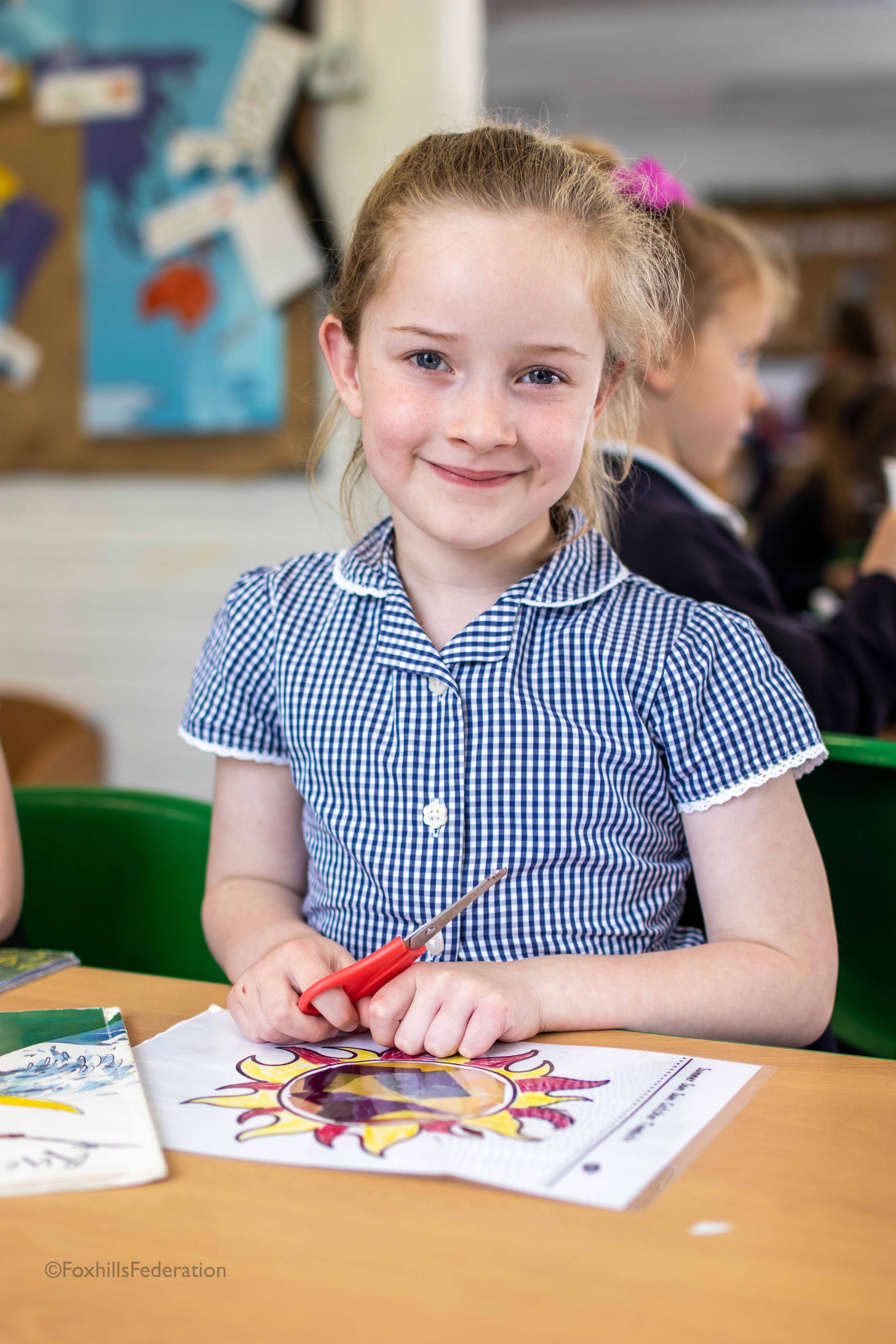 A girl smiles while cutting out colourful foil