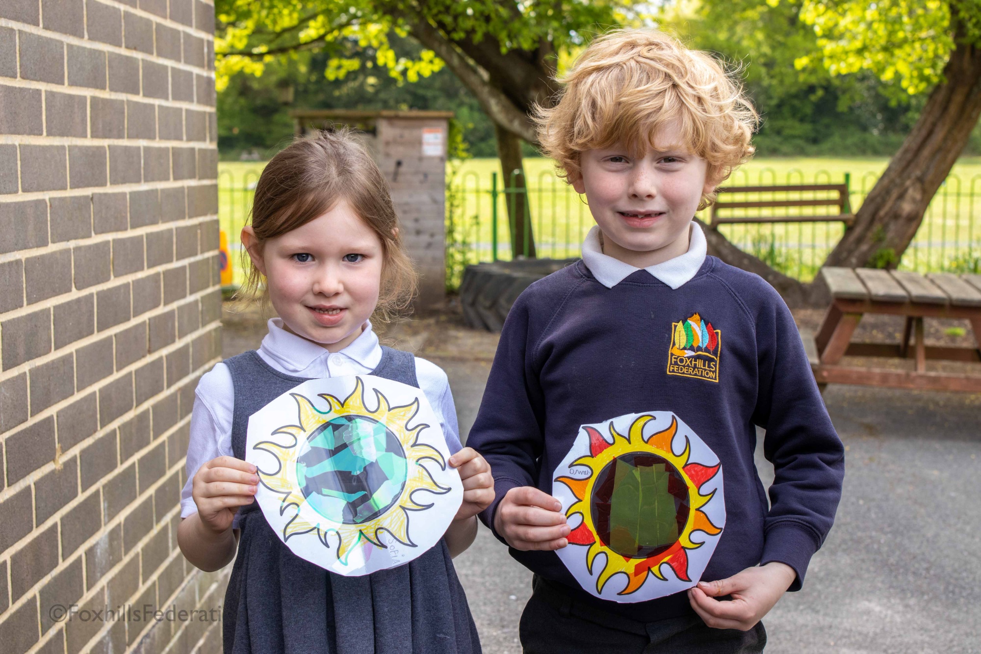 A boy and girl hold their sun catchers