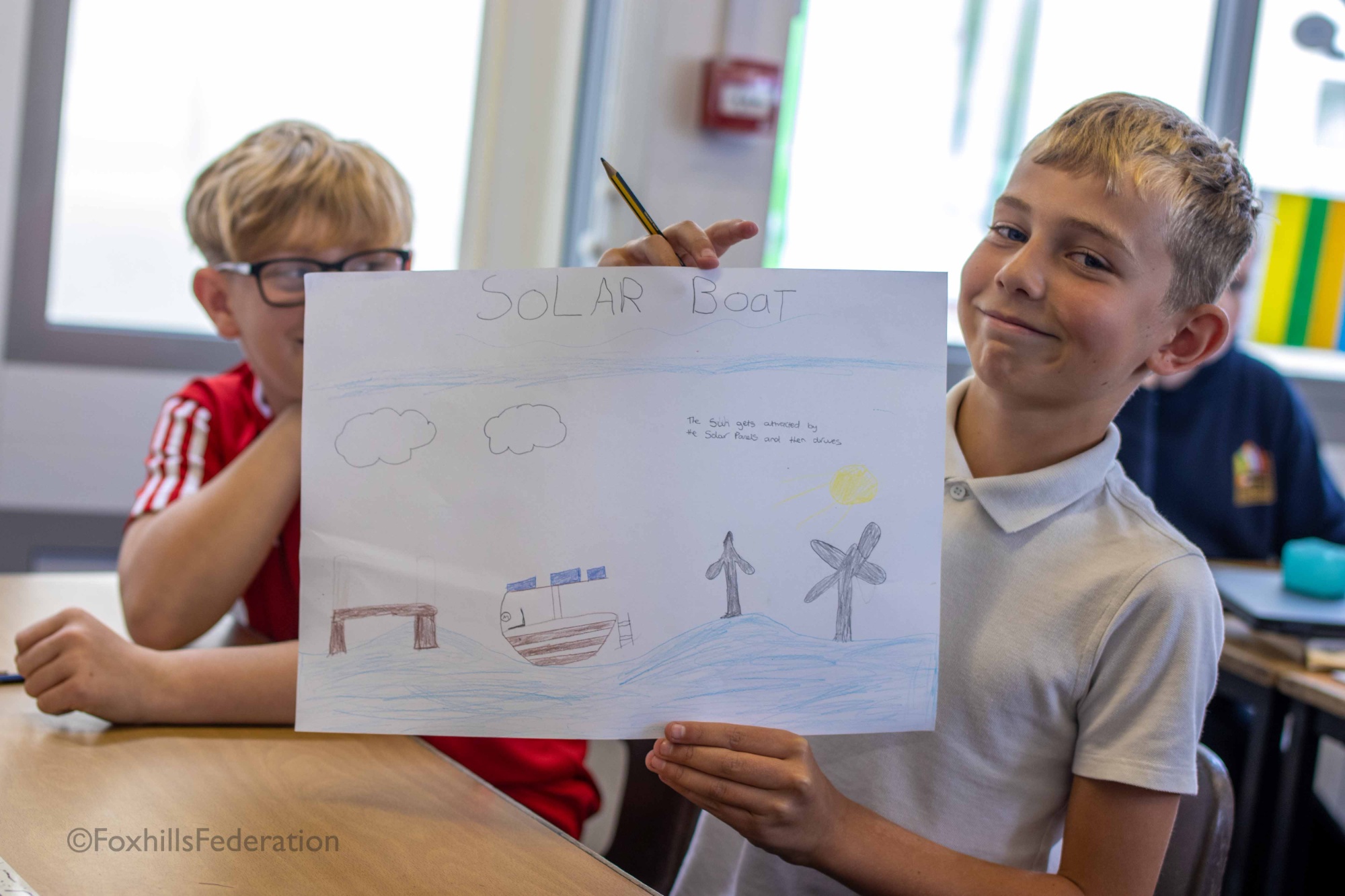Two boys hold up their renewable energy idea