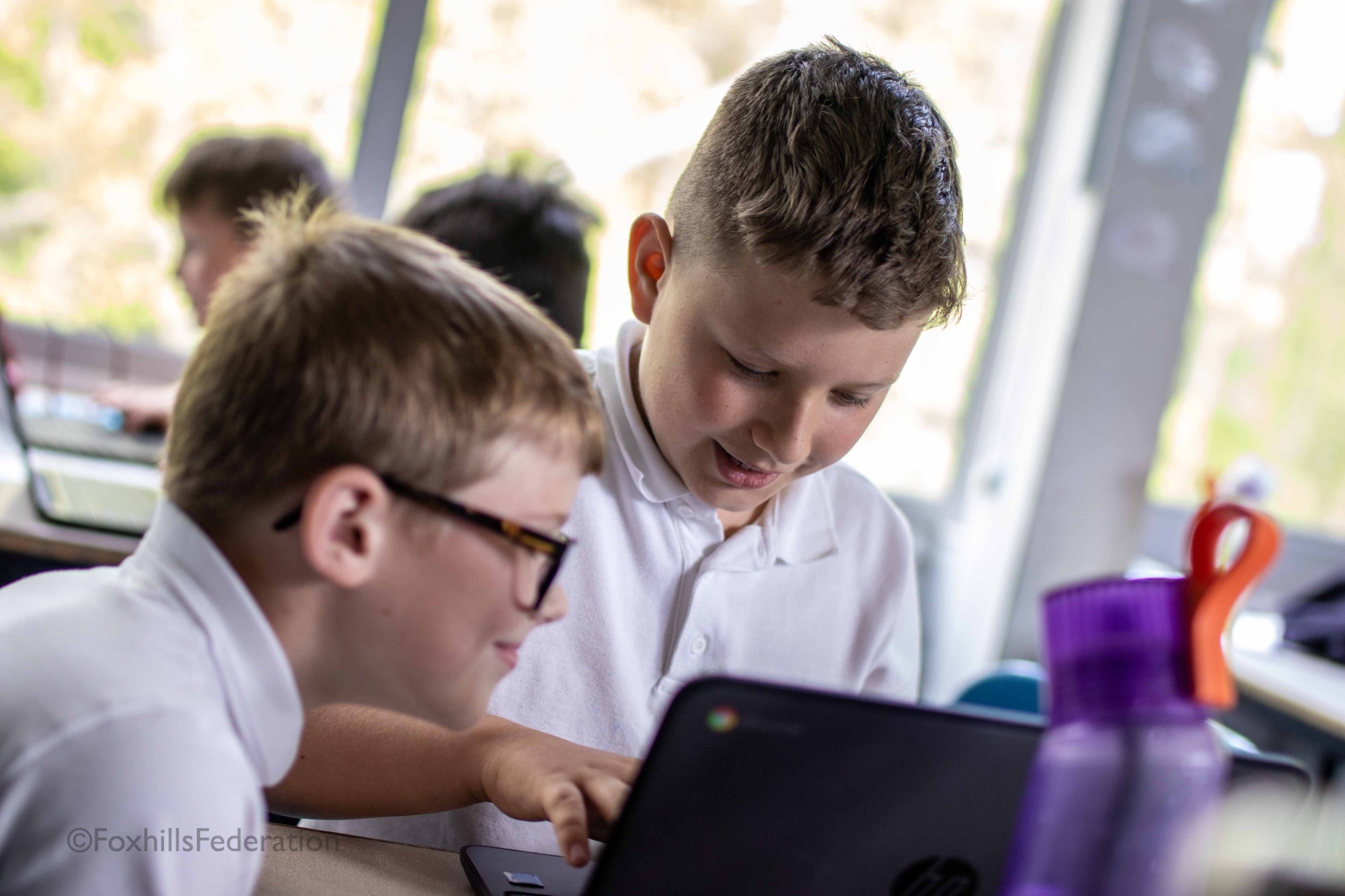 Two boys scroll through a spreadsheet