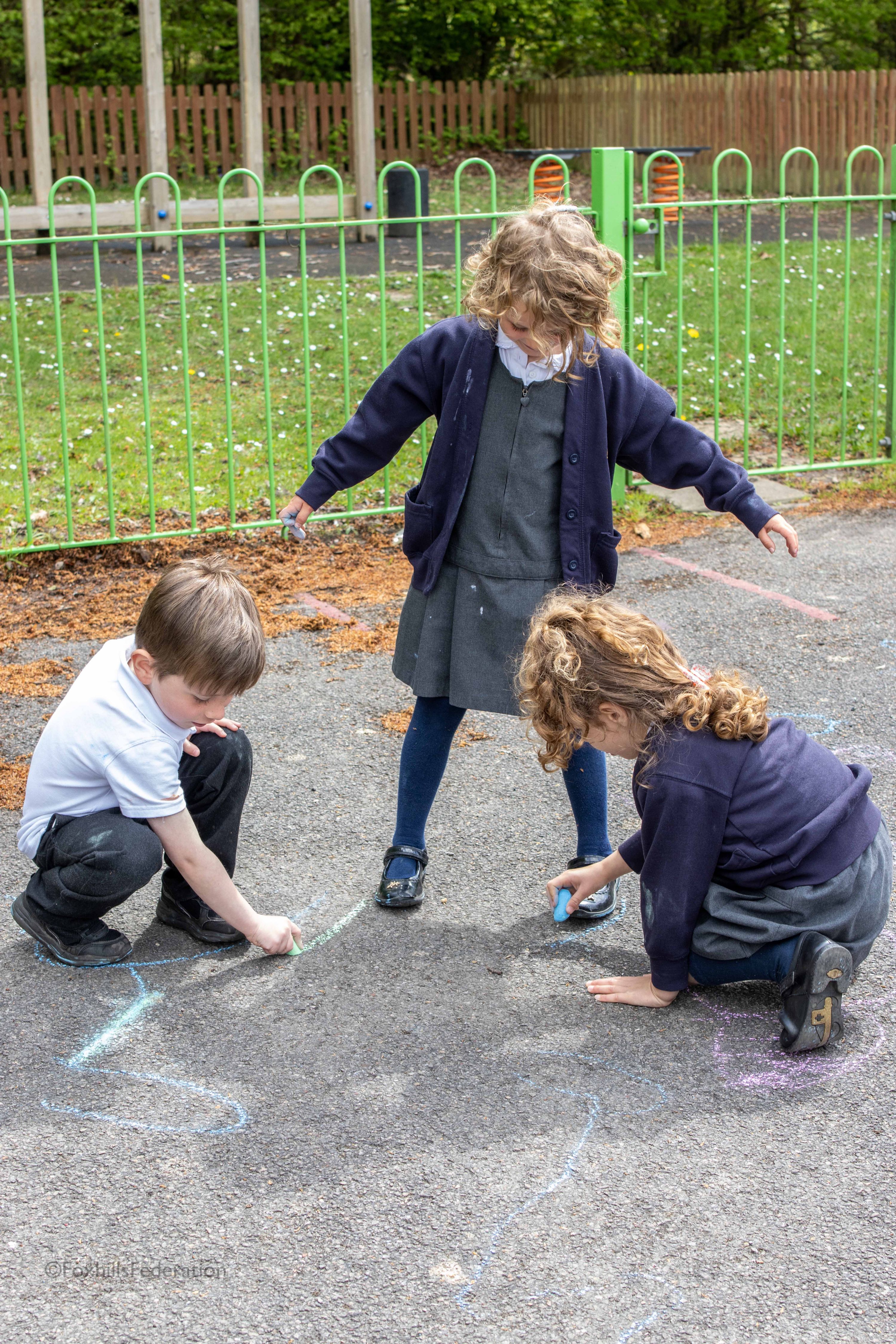 A Year R girl and boy draws around another girl's shadow