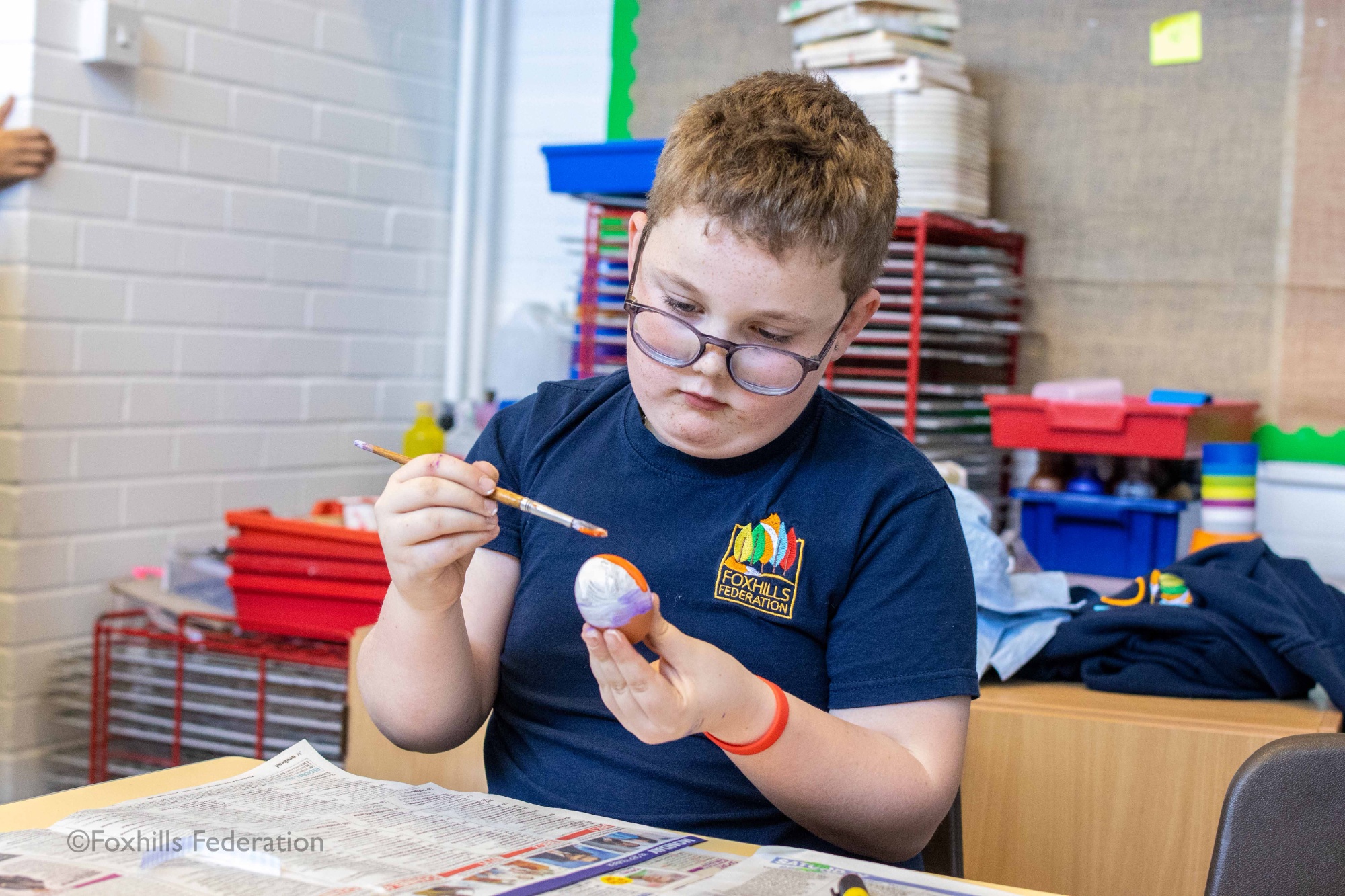 A boy paints a egg
