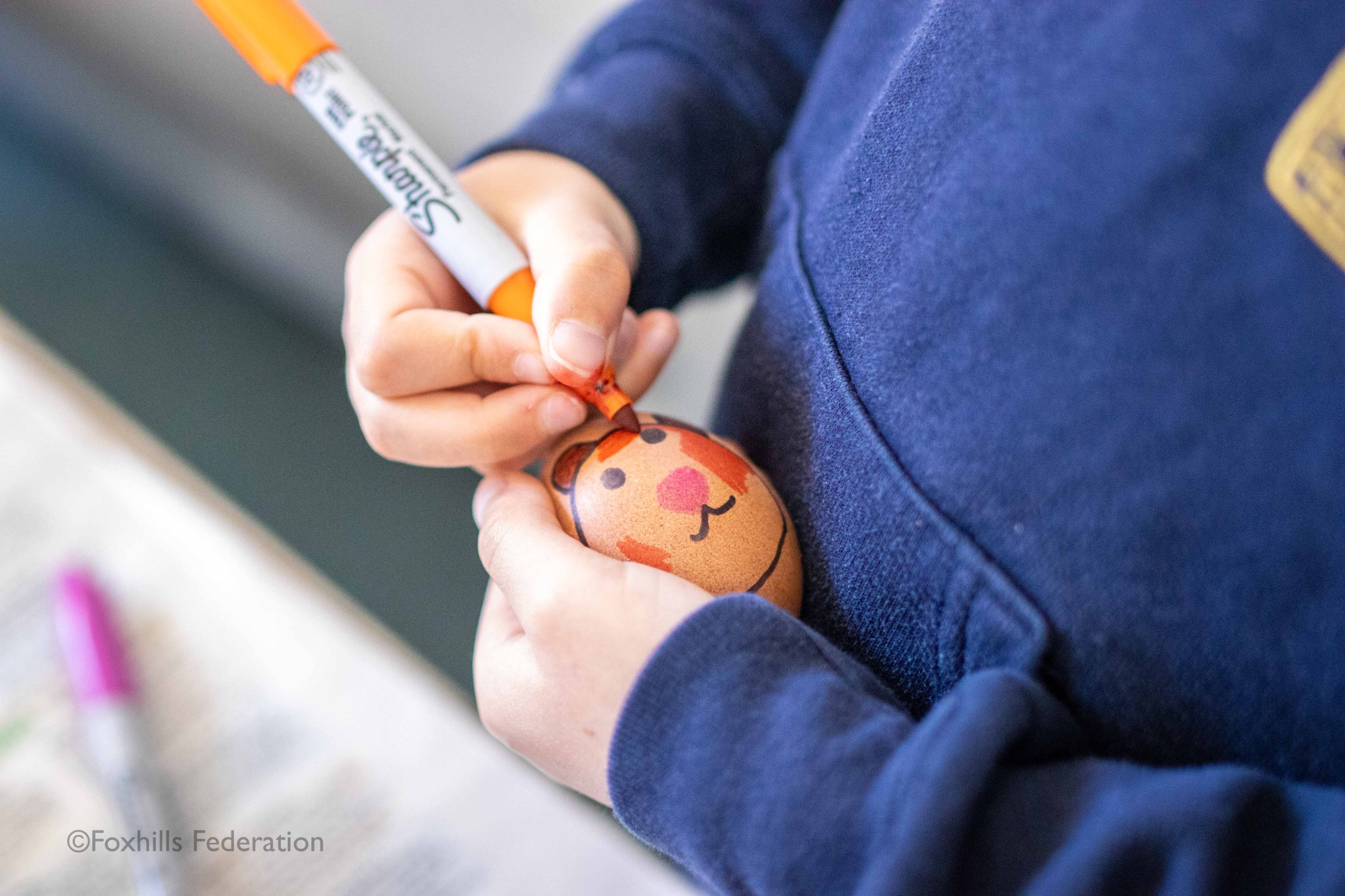 A child draws on an egg
