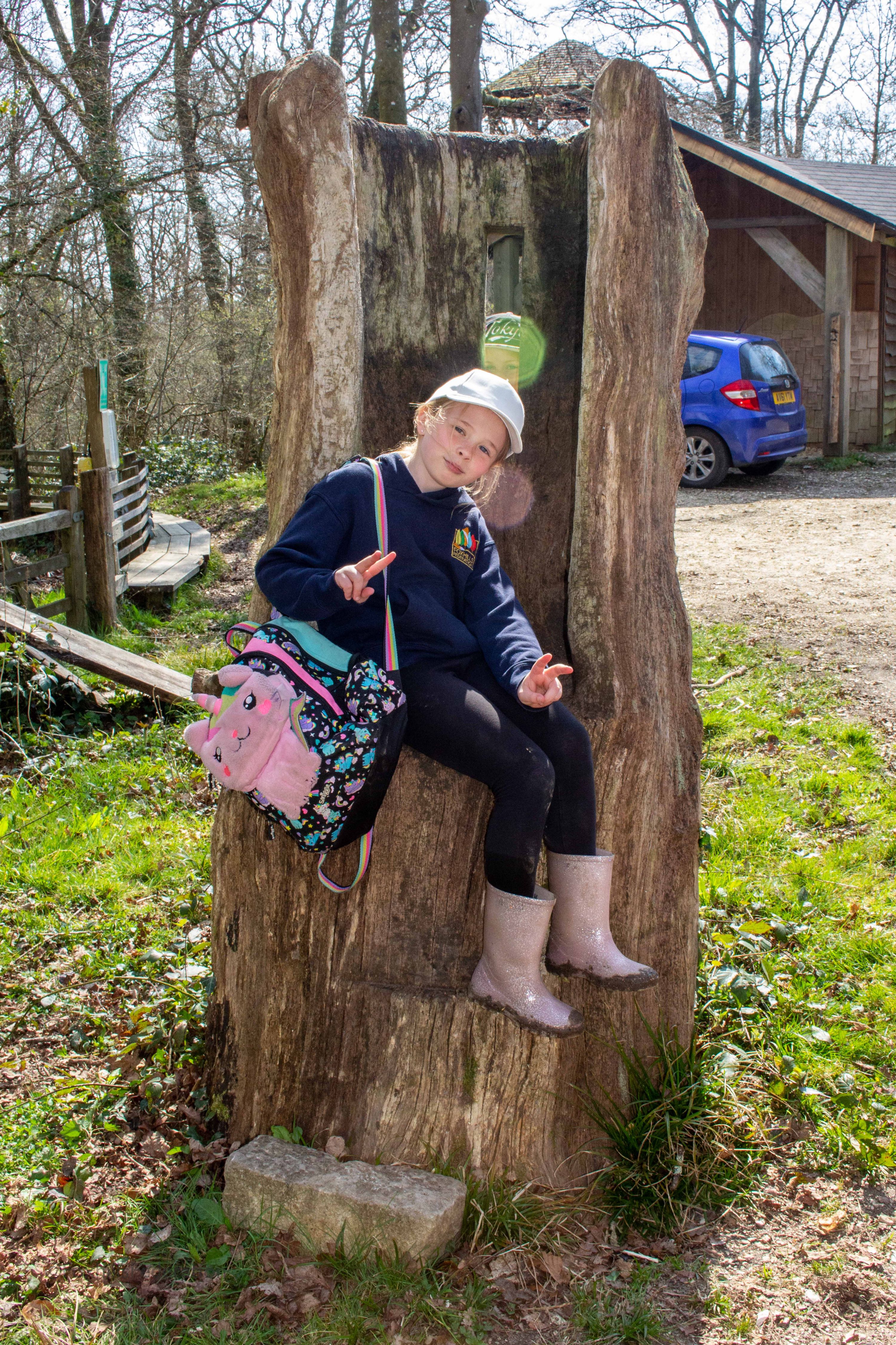 A girl sits on a tree stump
