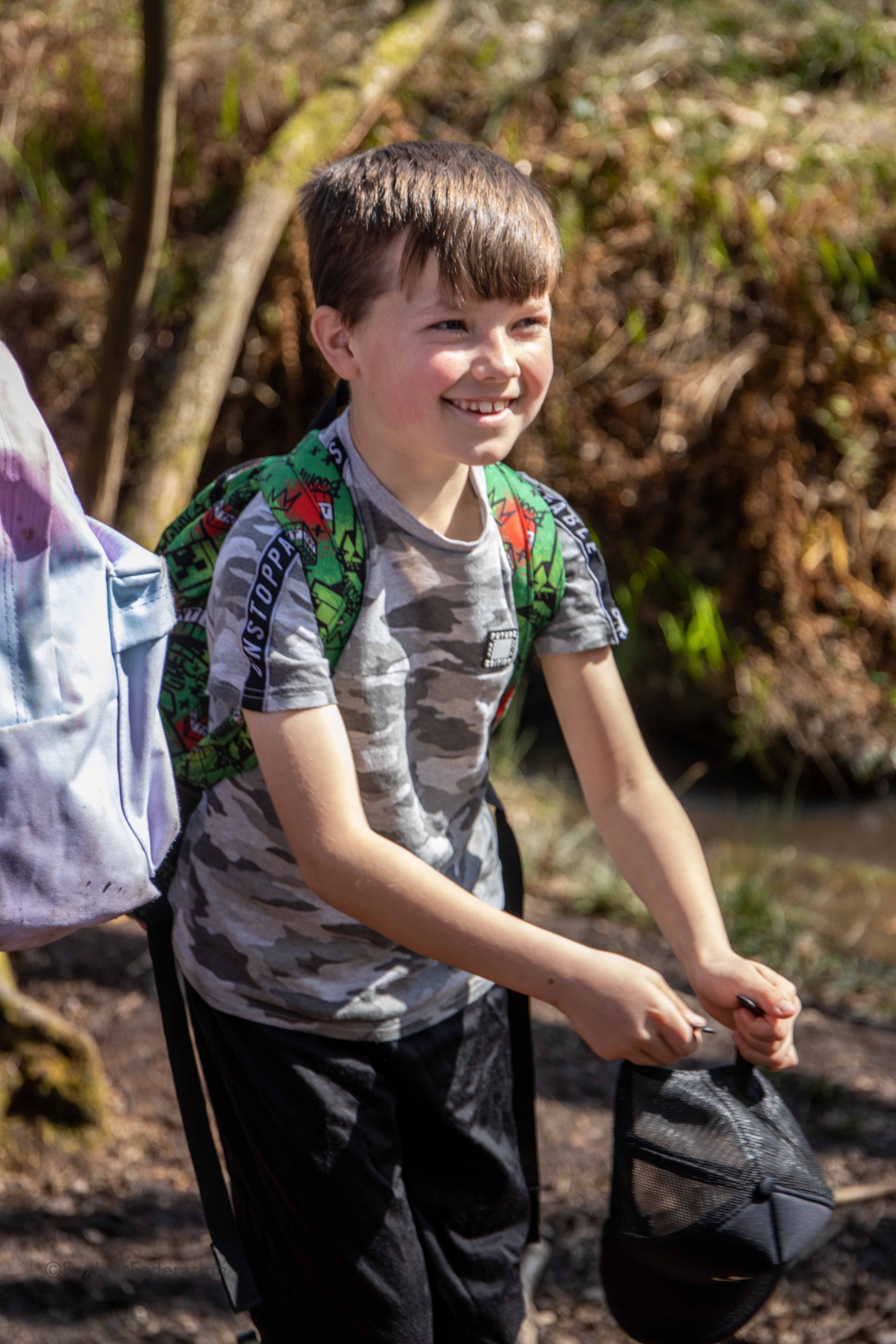 A boy smiles while holding a hat