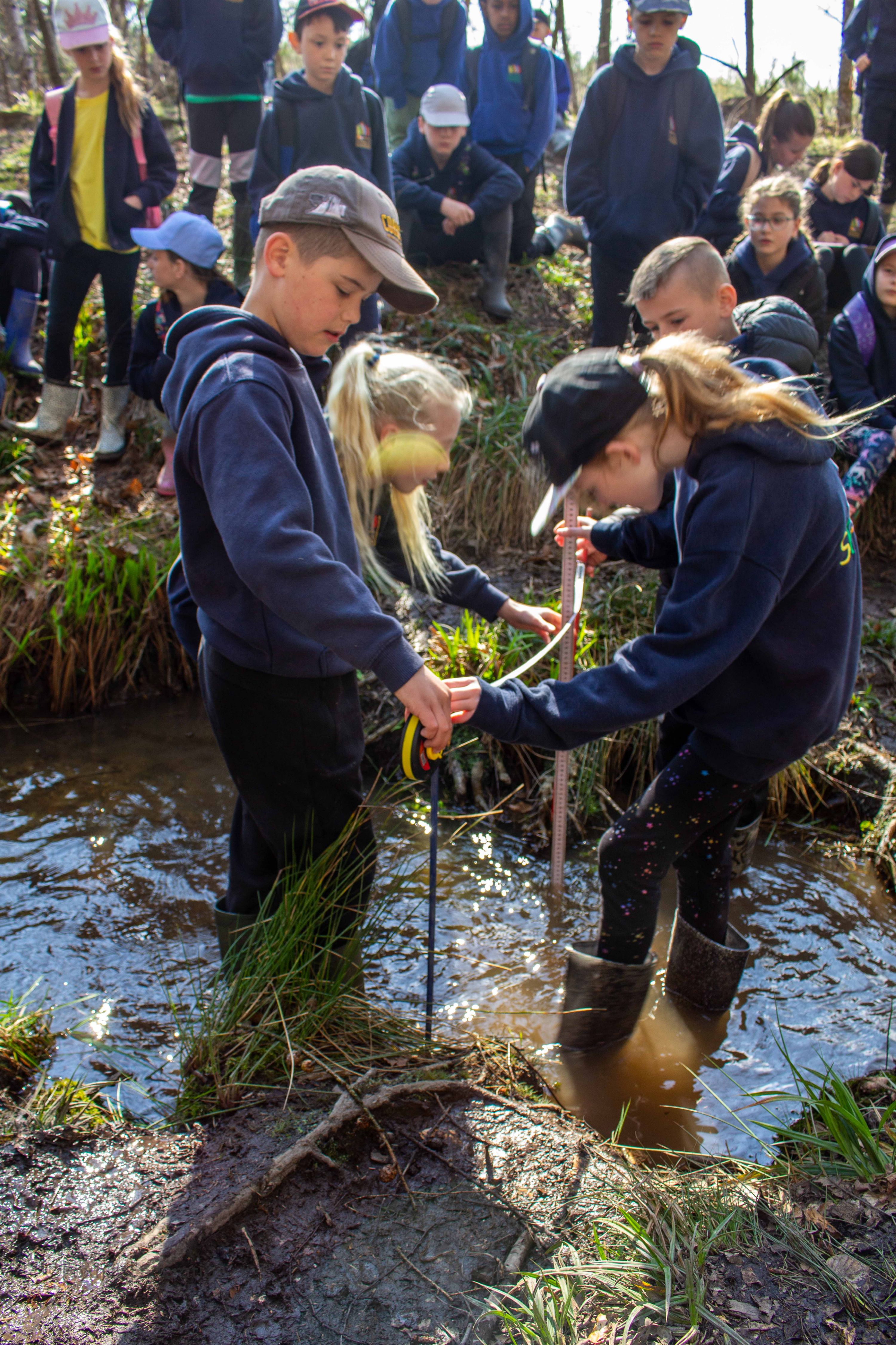 Children measure the depth of a stream