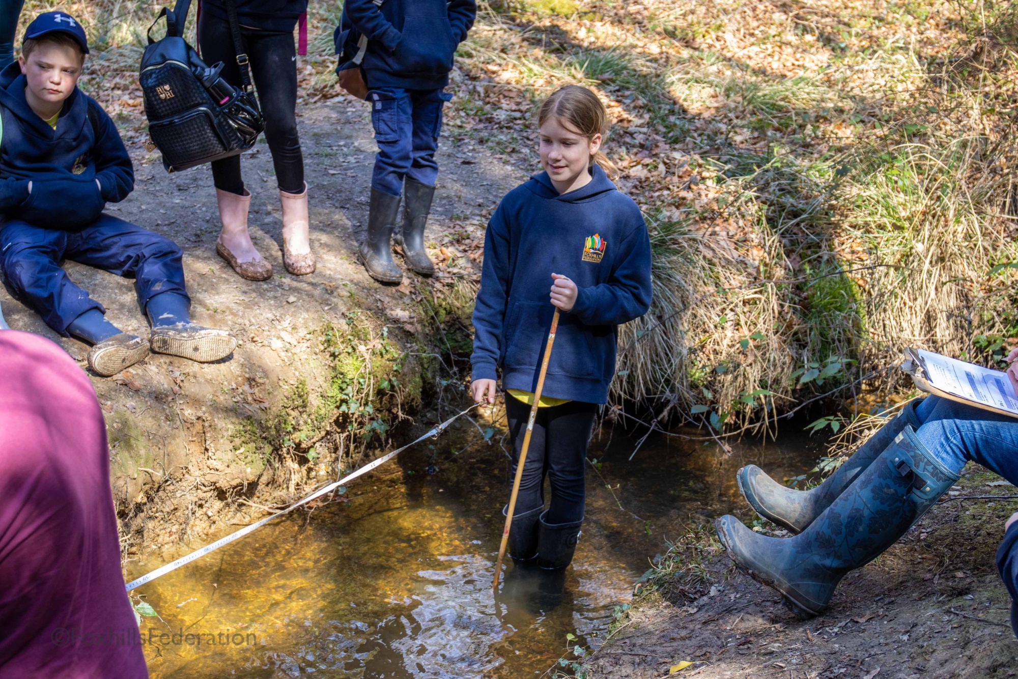 Children measure the depth of a stream