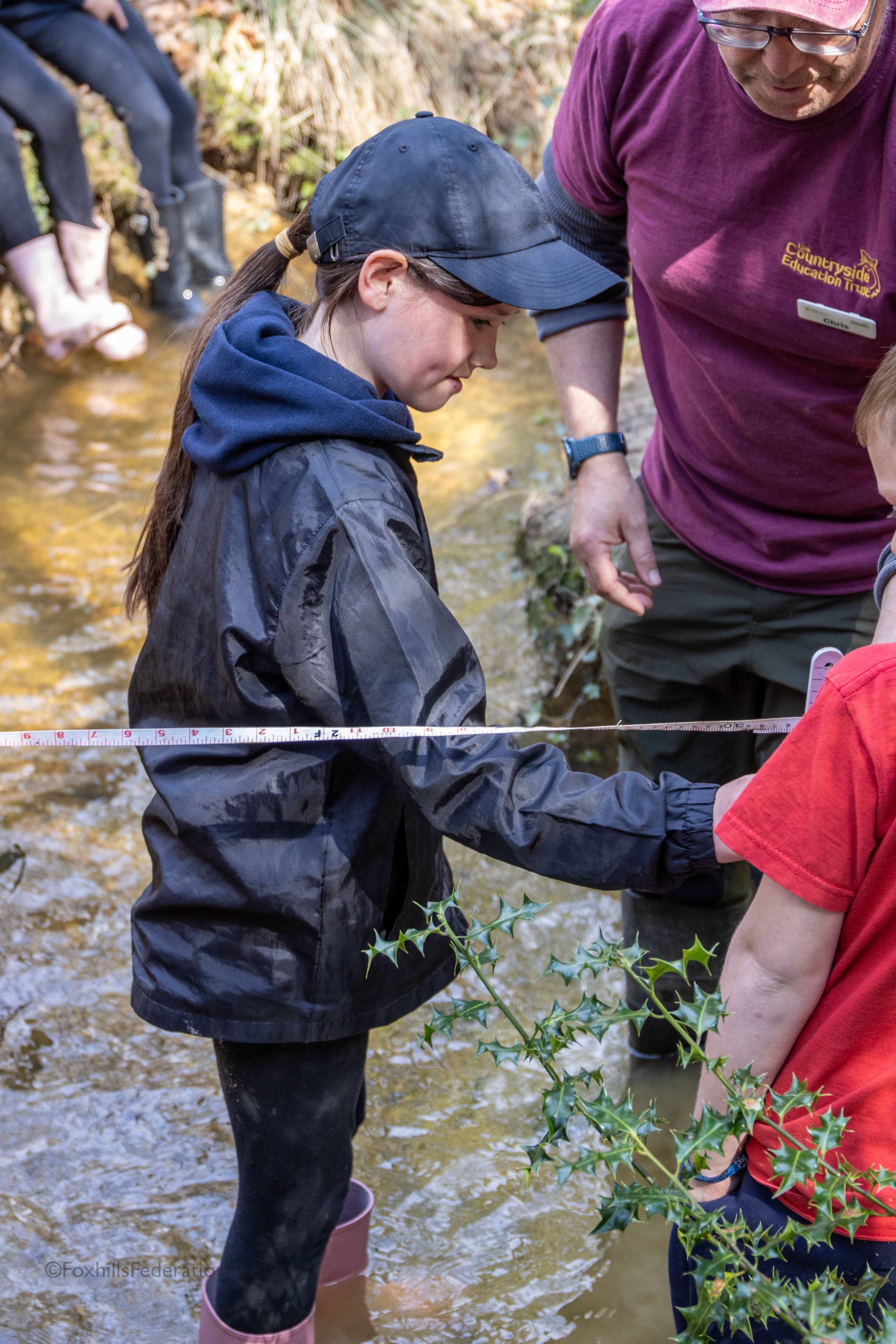 Children measure the depth of a stream