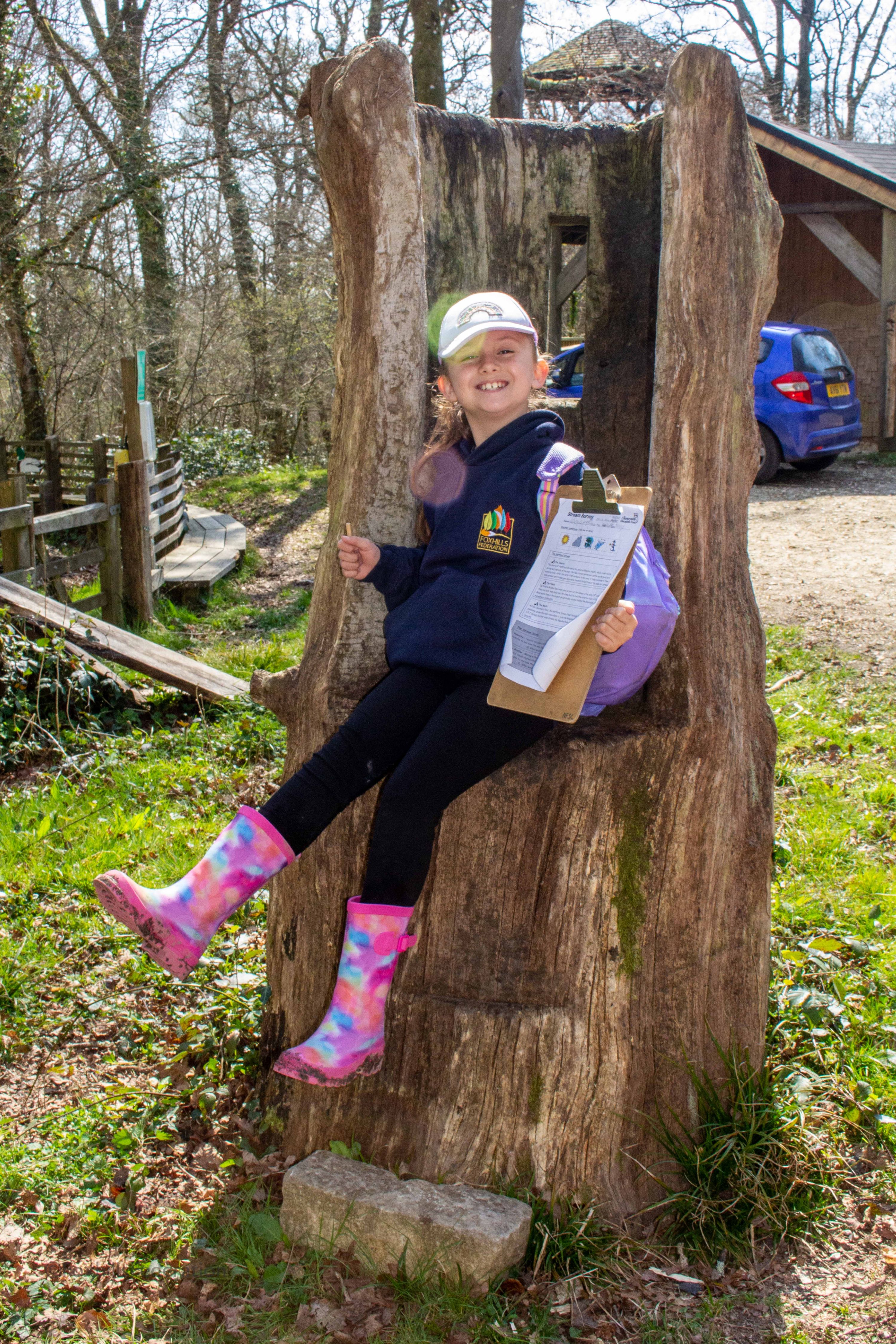 A girl sits on a tree stump