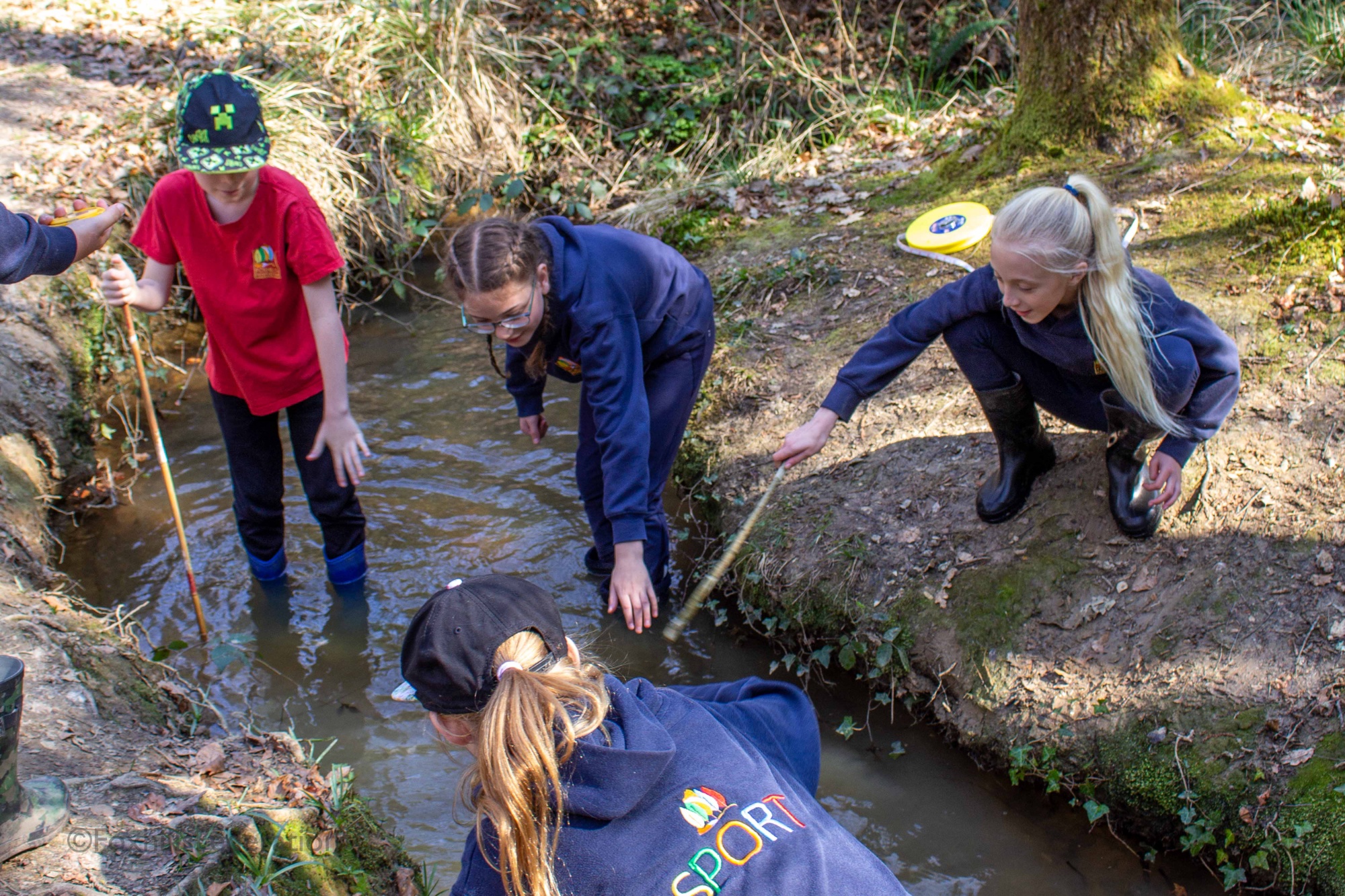 Children measure the depth of a stream
