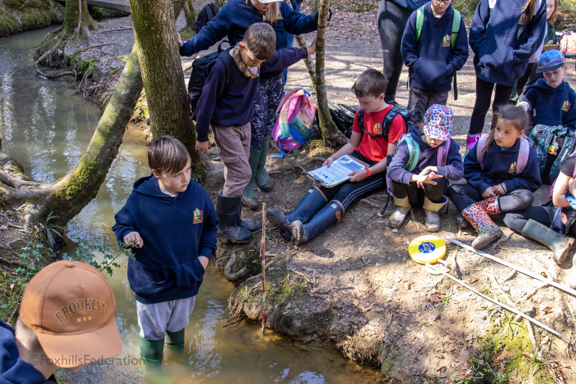 A boy stands in a stream about to measure the speed of the water
