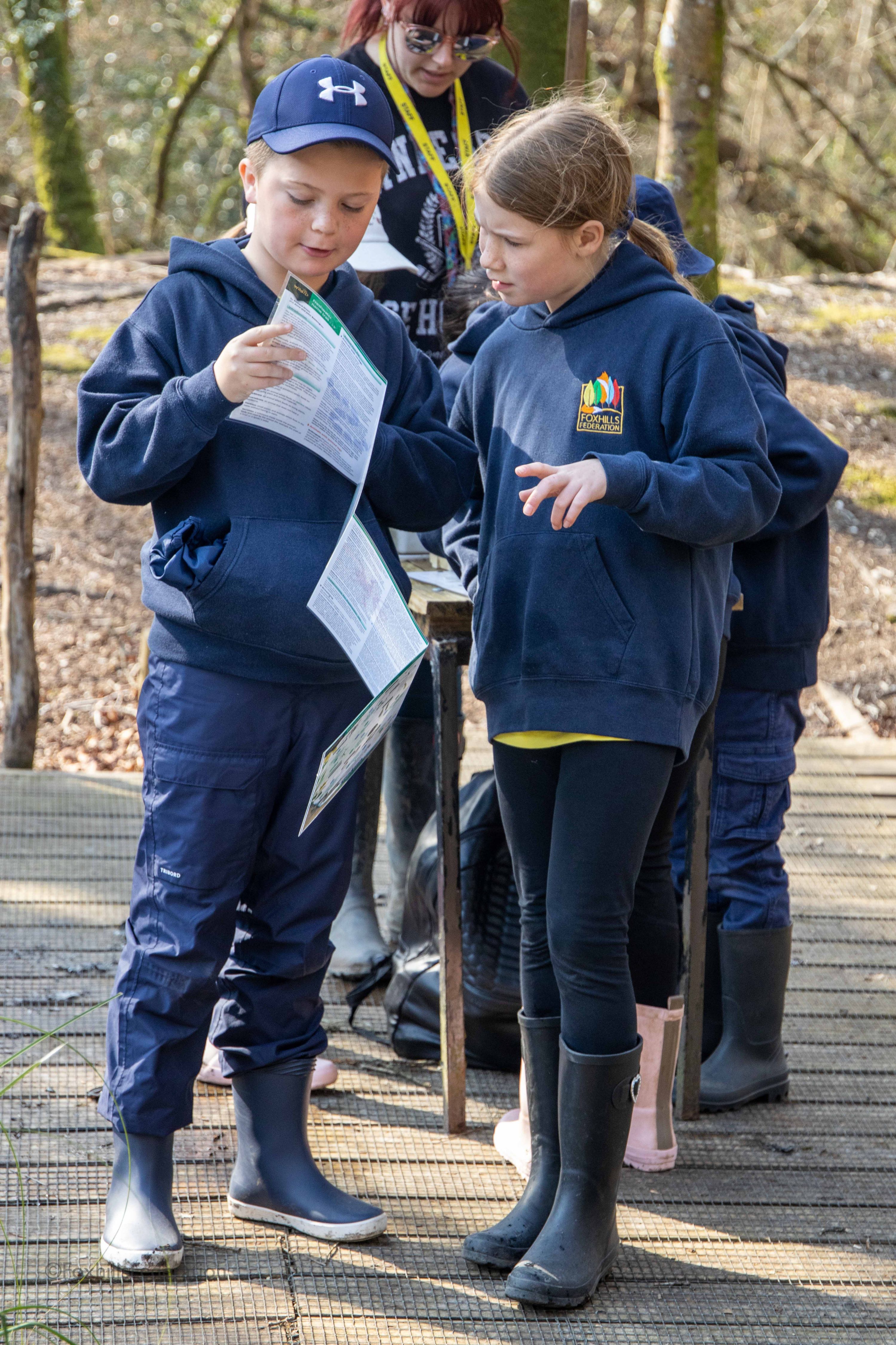 Two children try to identify creatures they have just found
