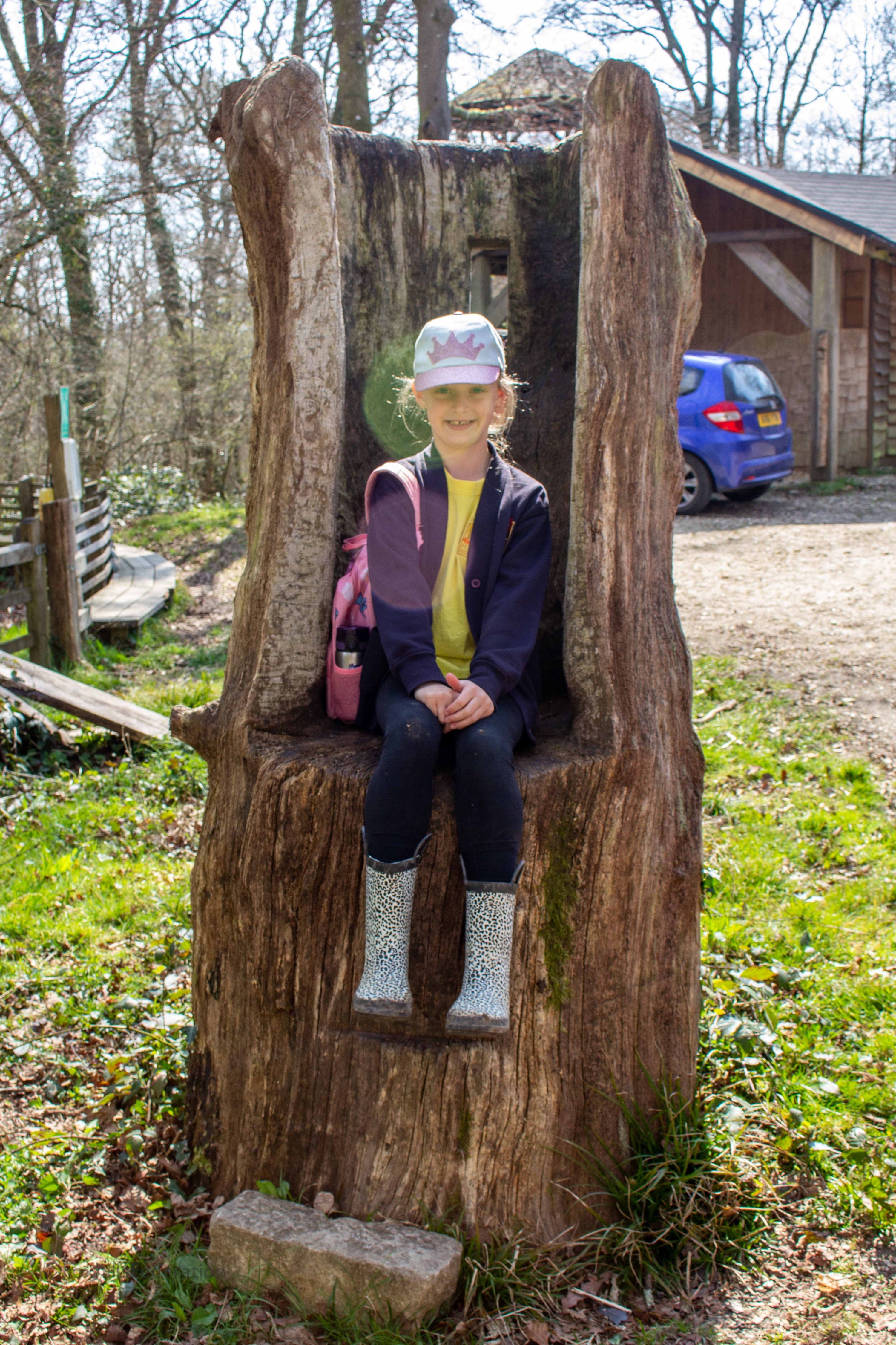 A girl sits on a tree stump