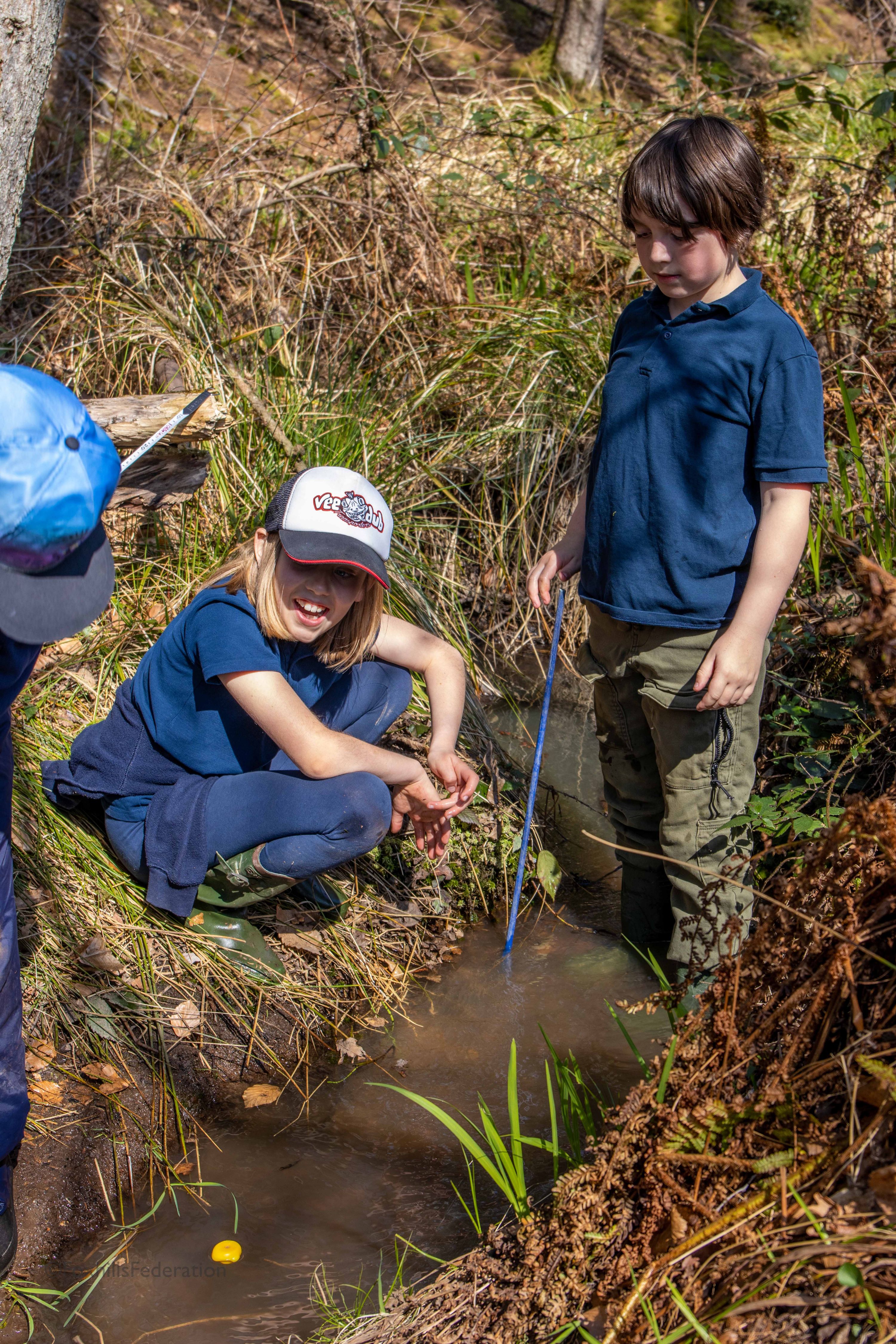 Children measure the depth of a stream