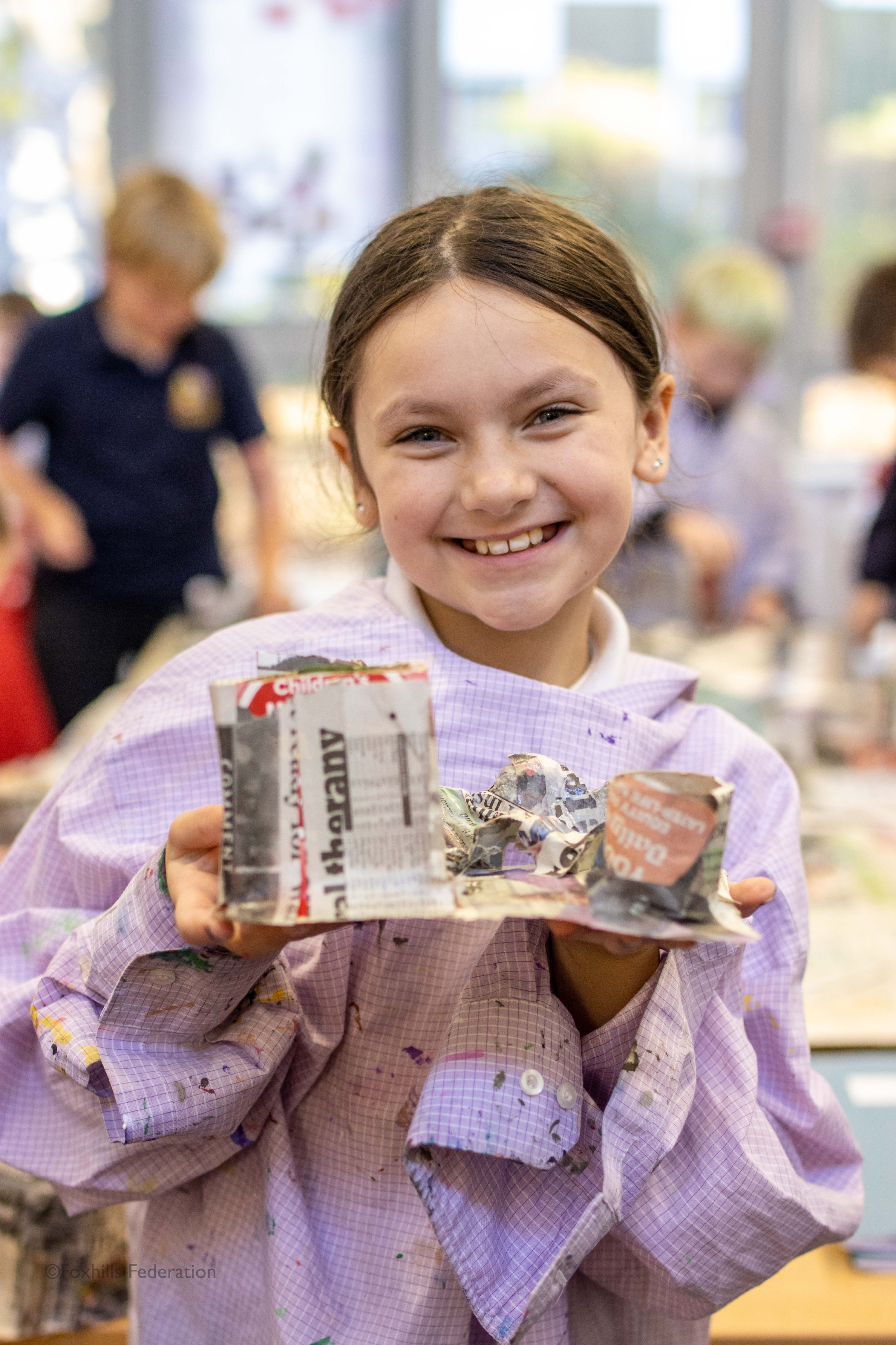 A girl smiles and holds a homemade desk tidy.