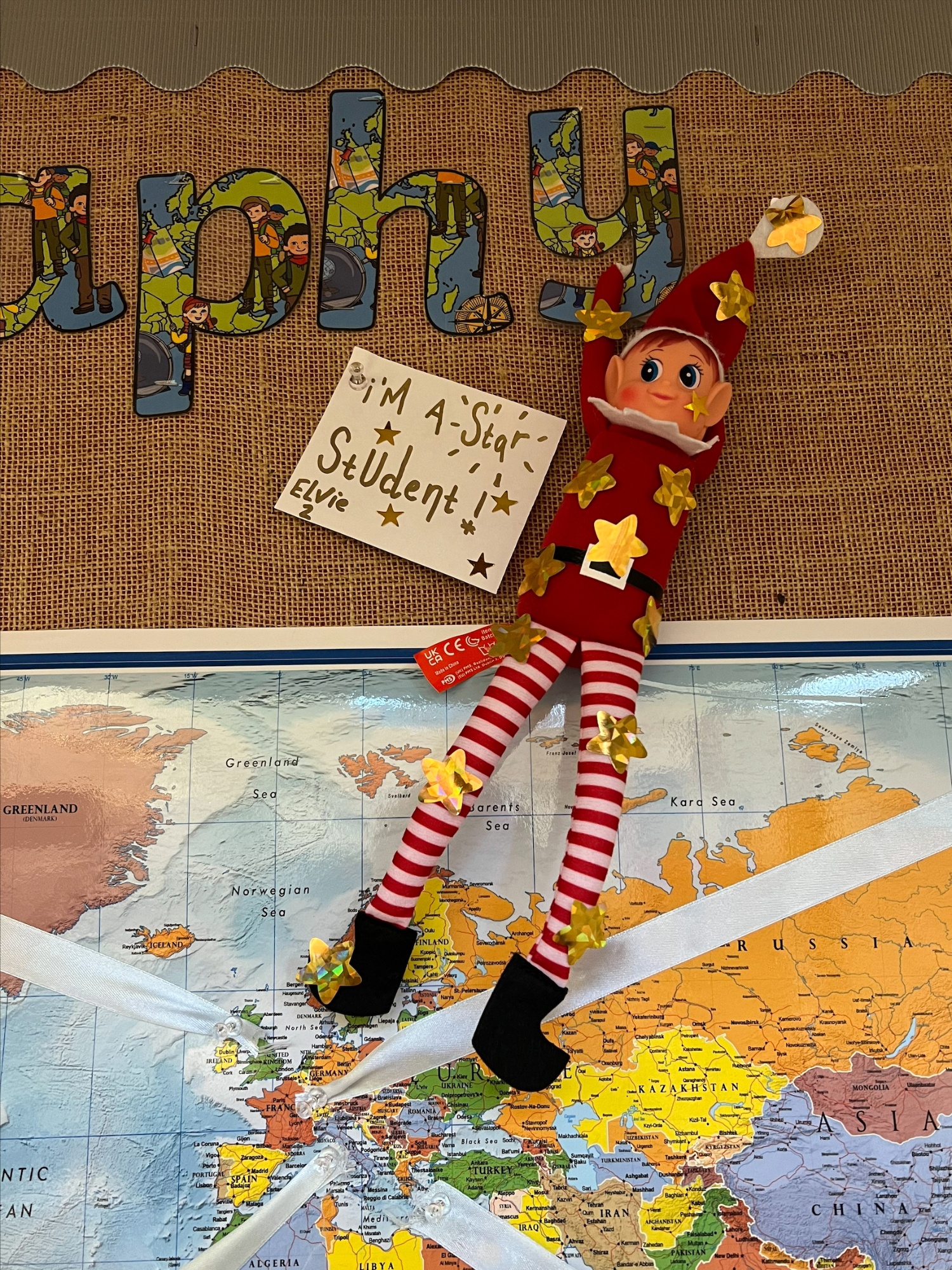 An elf pinned to a classroom display board.