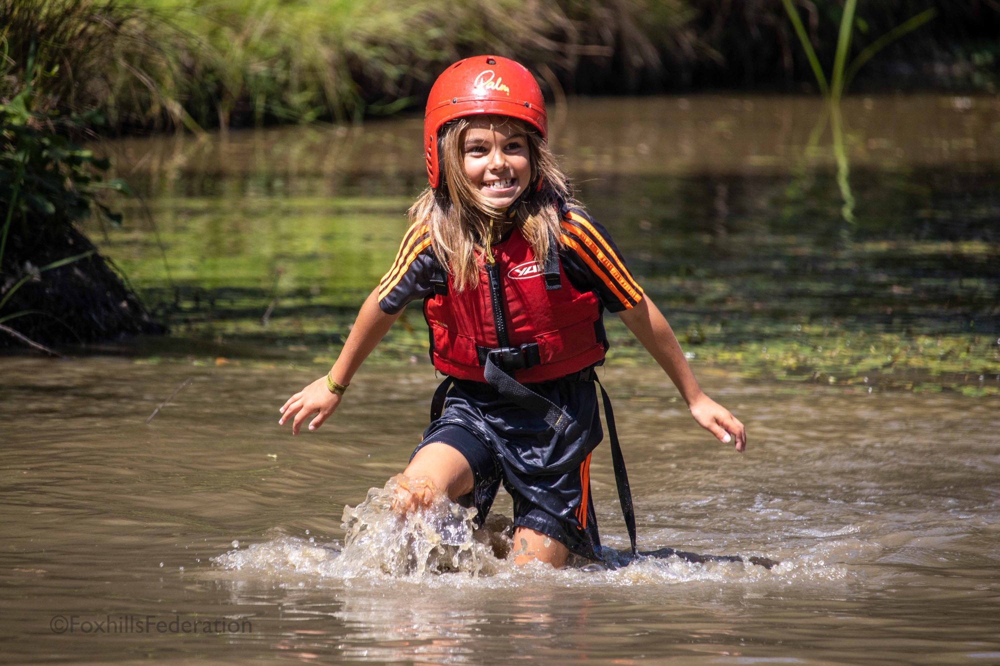 A boy paddles through a pond