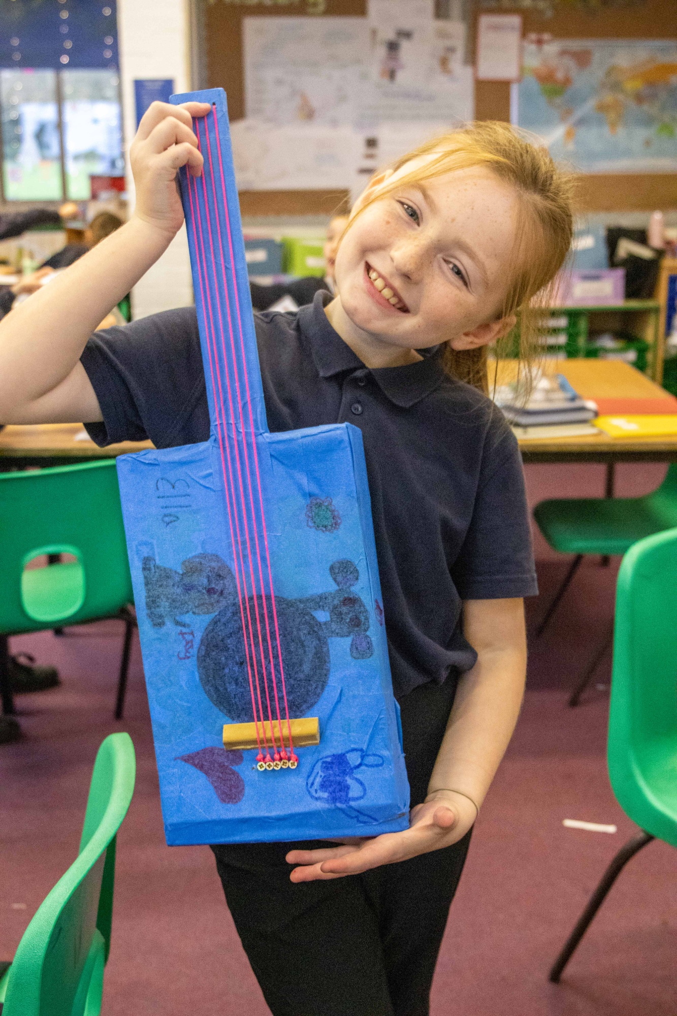 A girl holds a homemade music instrument.
