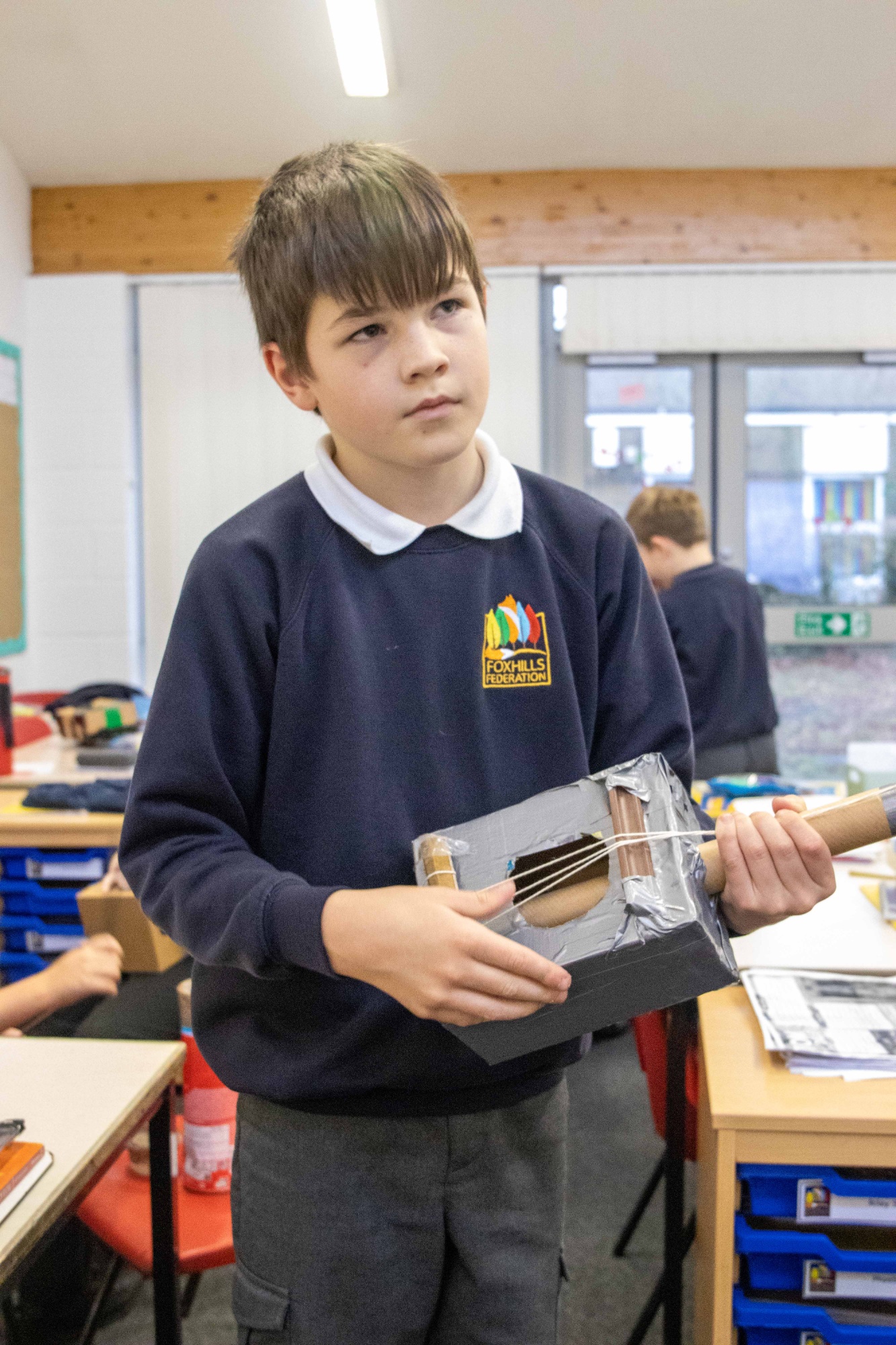 A boy plays a homemade music instrument.