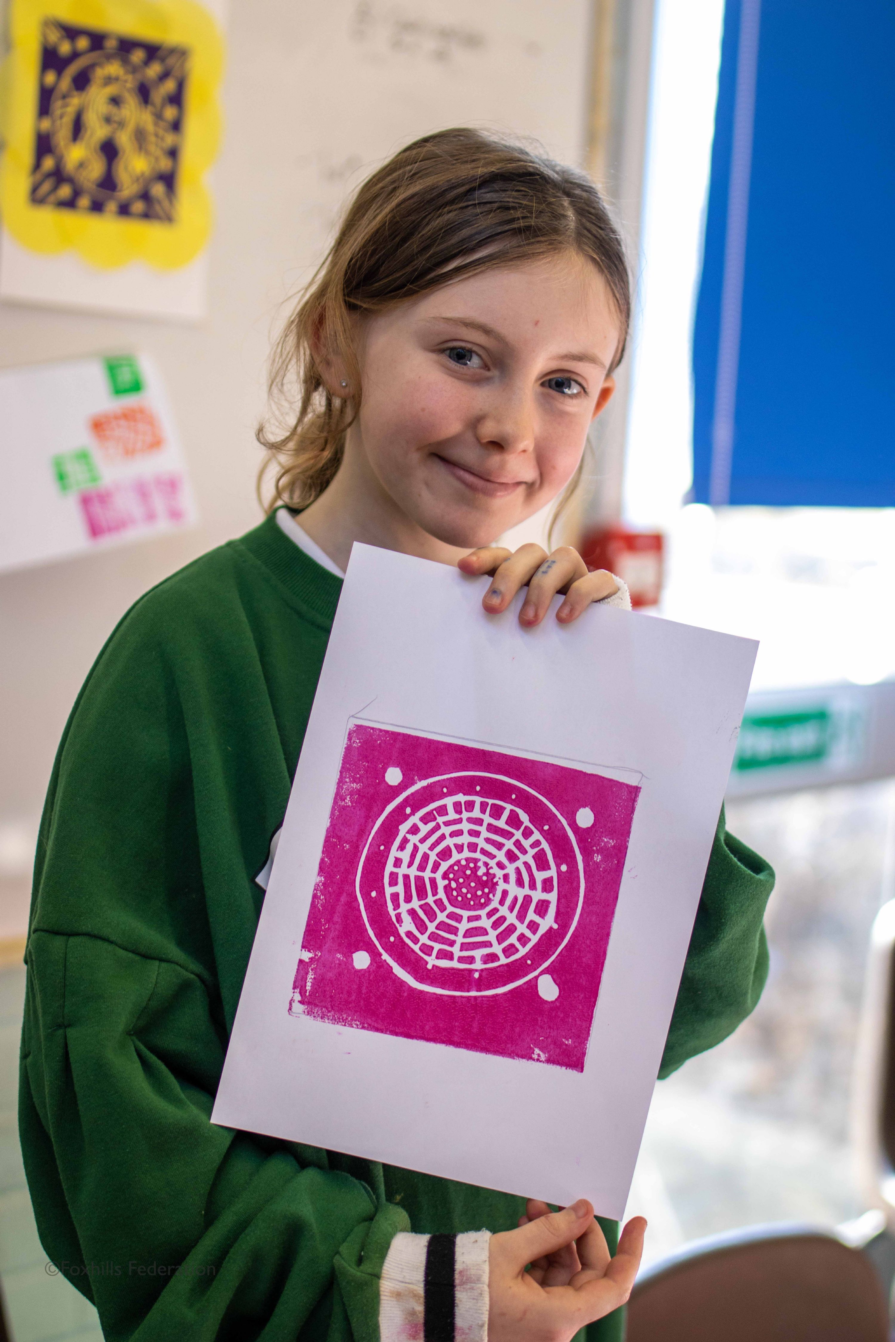 A girl holds up work created by stamp printing.