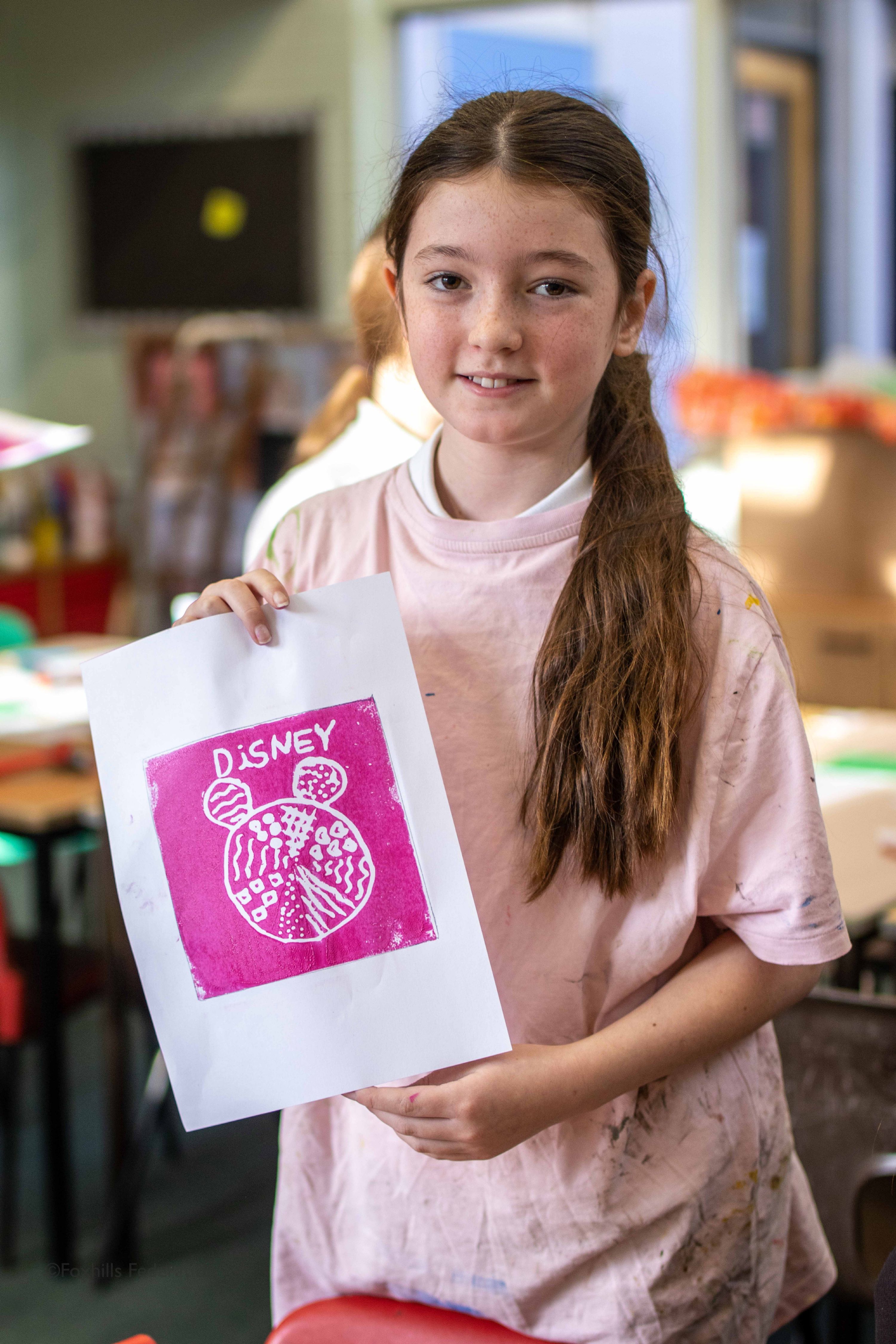 A girl holds up work created by stamp printing.