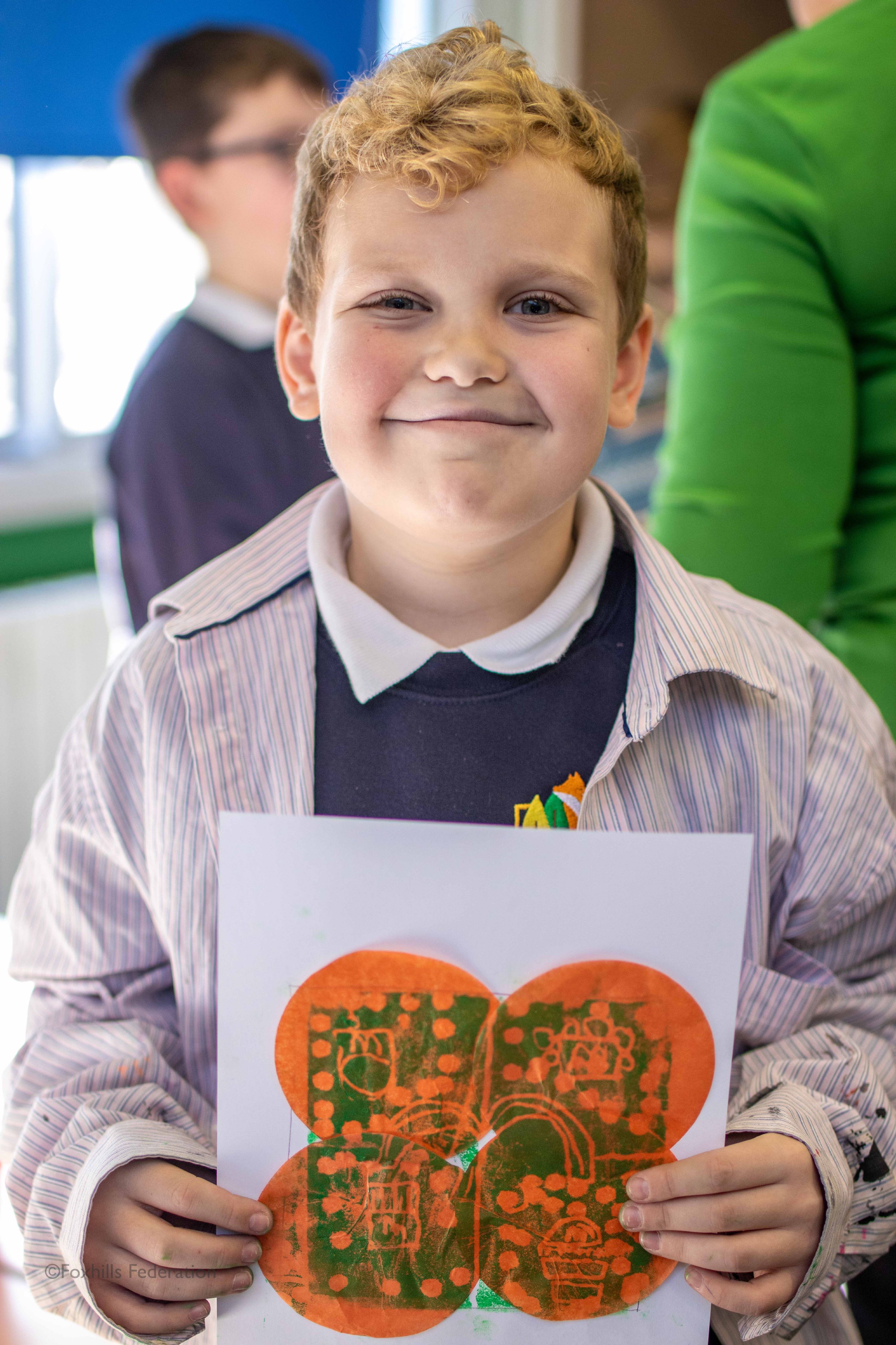 A boy holds up work created by stamp printing.