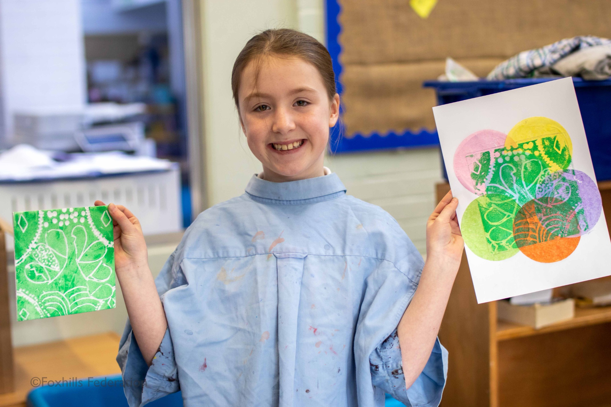 A girl holds up work created by stamp printing.