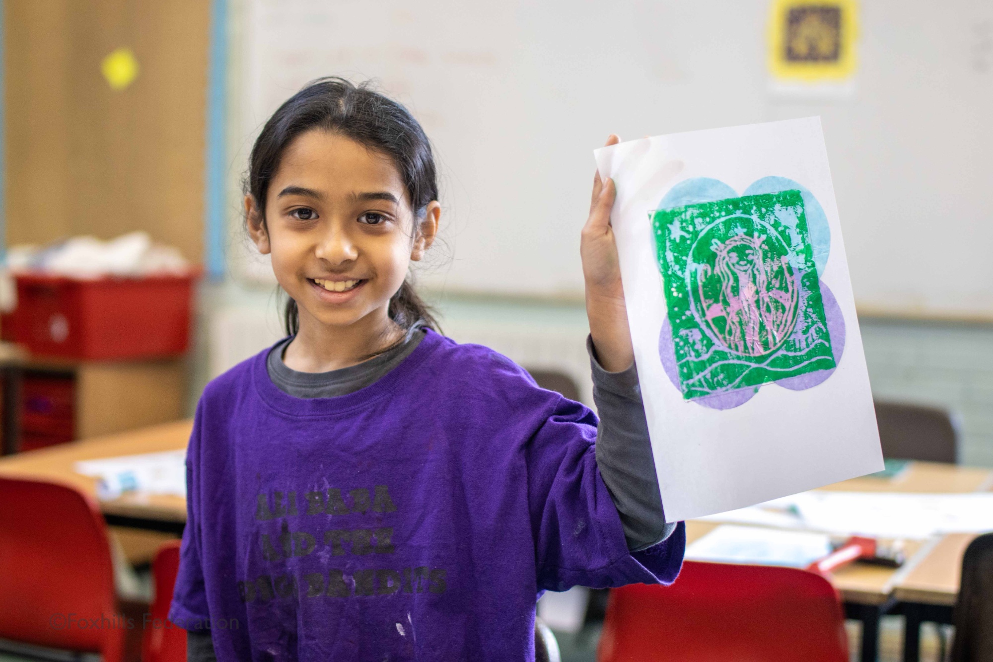A girl holds up work created by stamp printing.