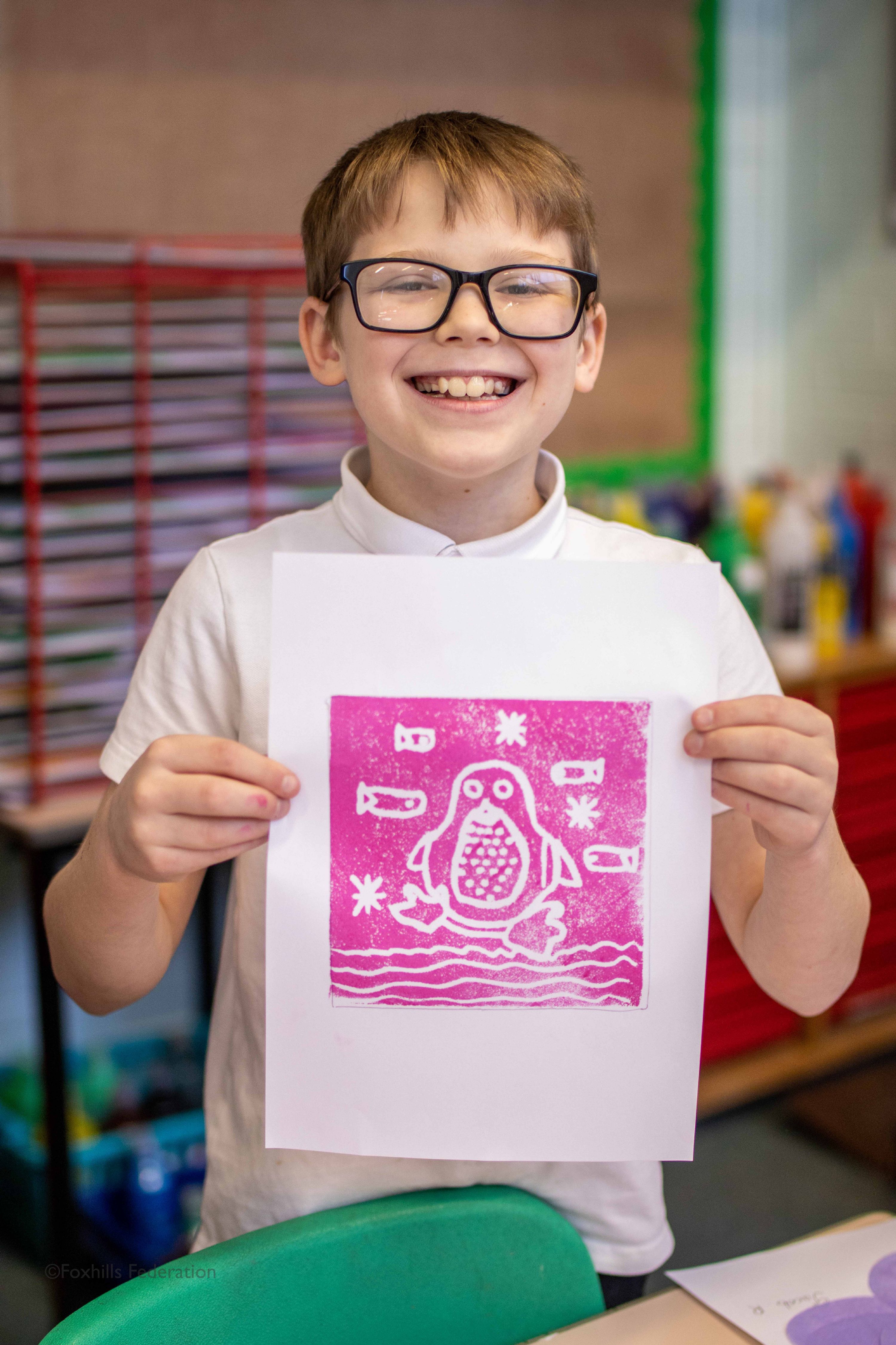 A boy holds up work created by stamp printing.