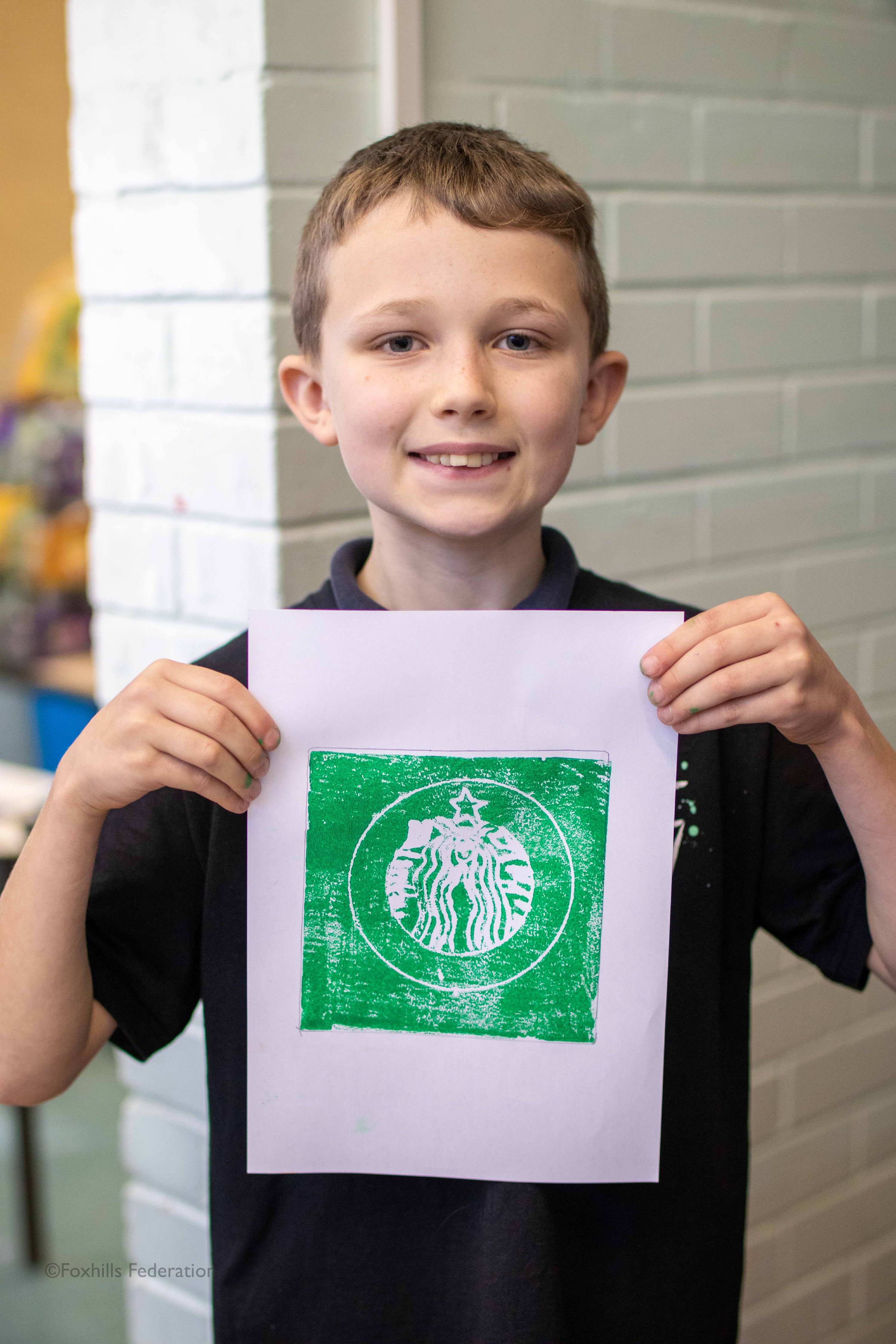 A boy holds up work created by stamp printing.