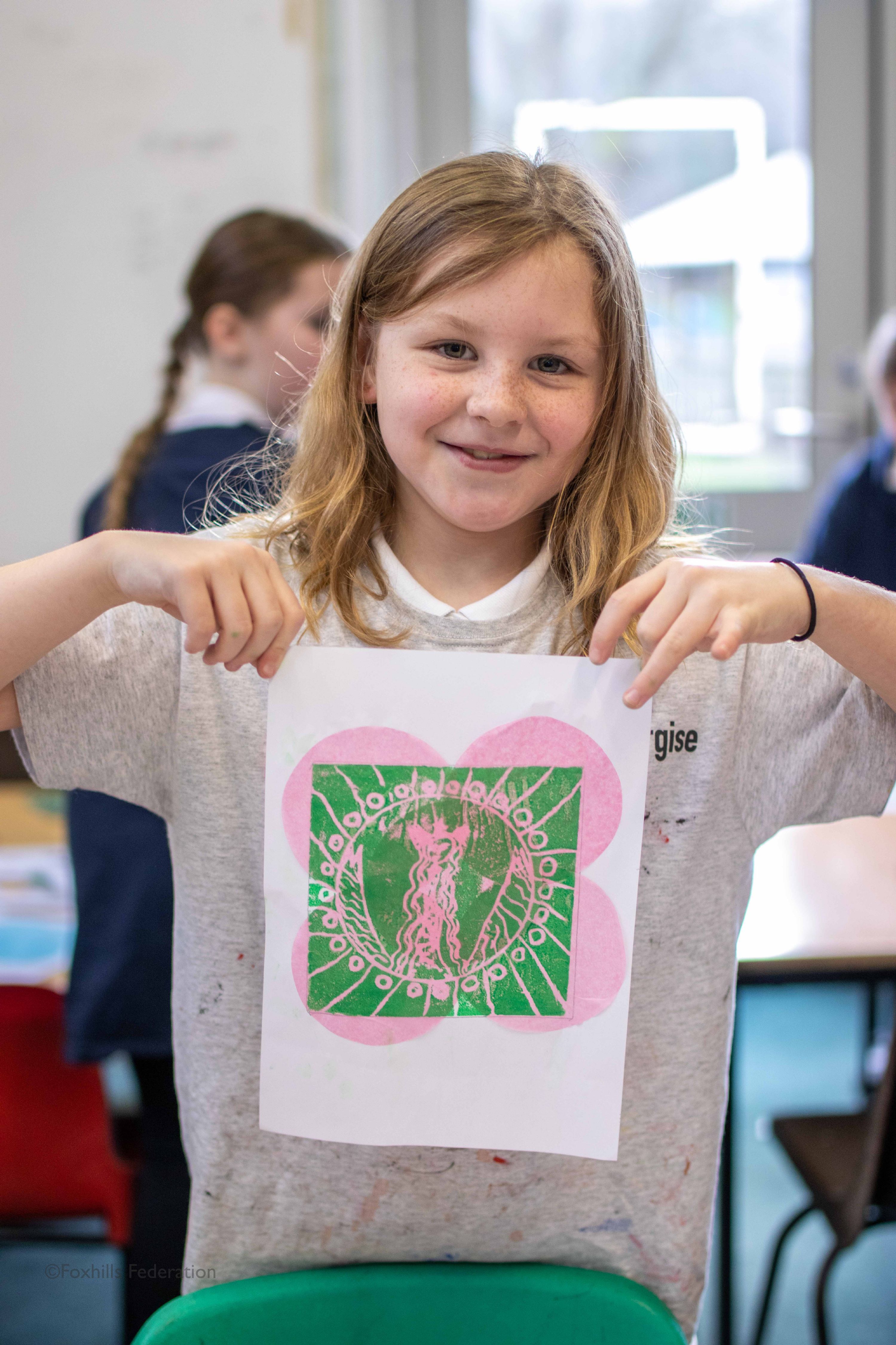 A girl holds up work created by stamp printing.
