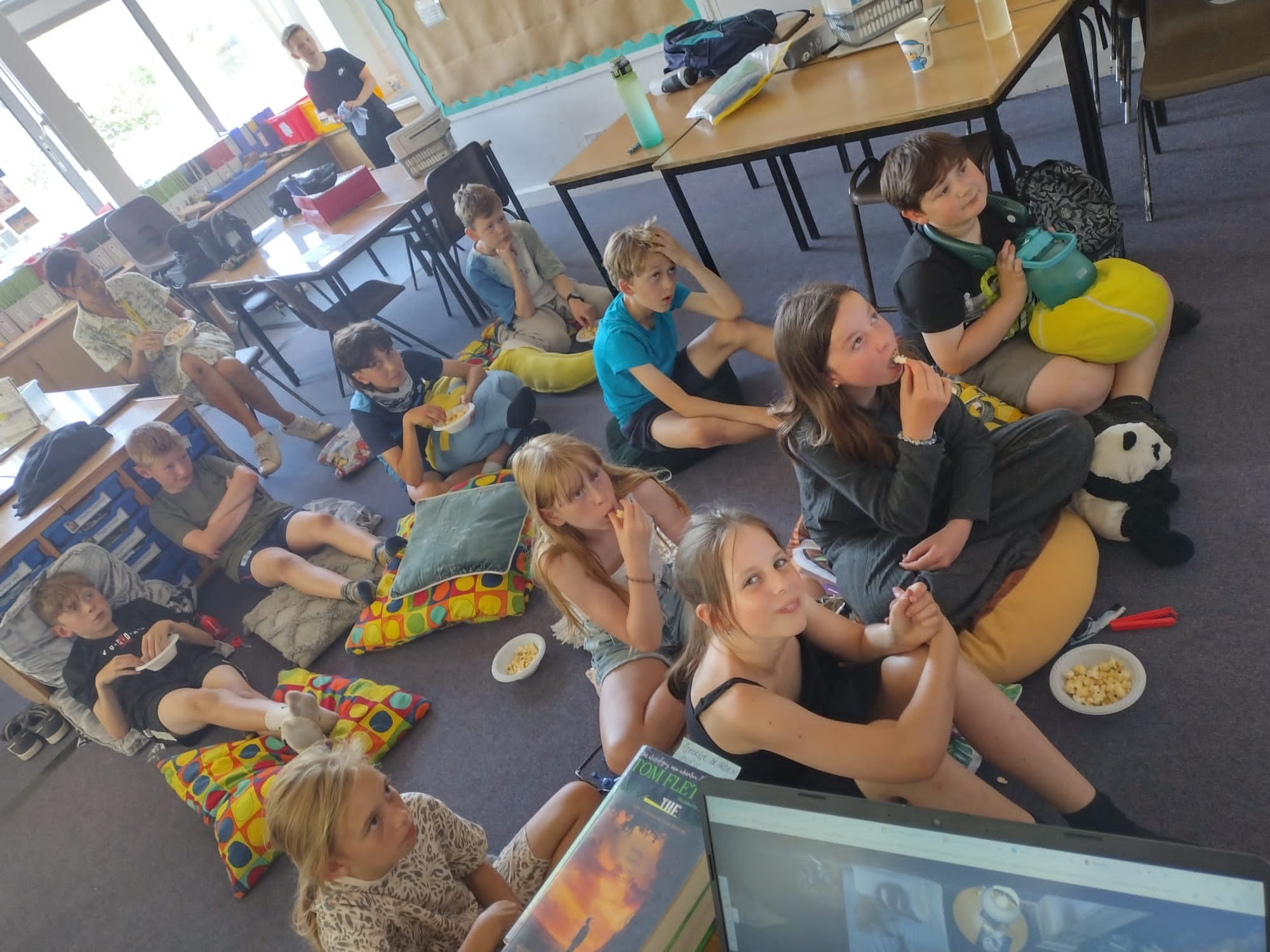 Children watch a movie while eating pizza