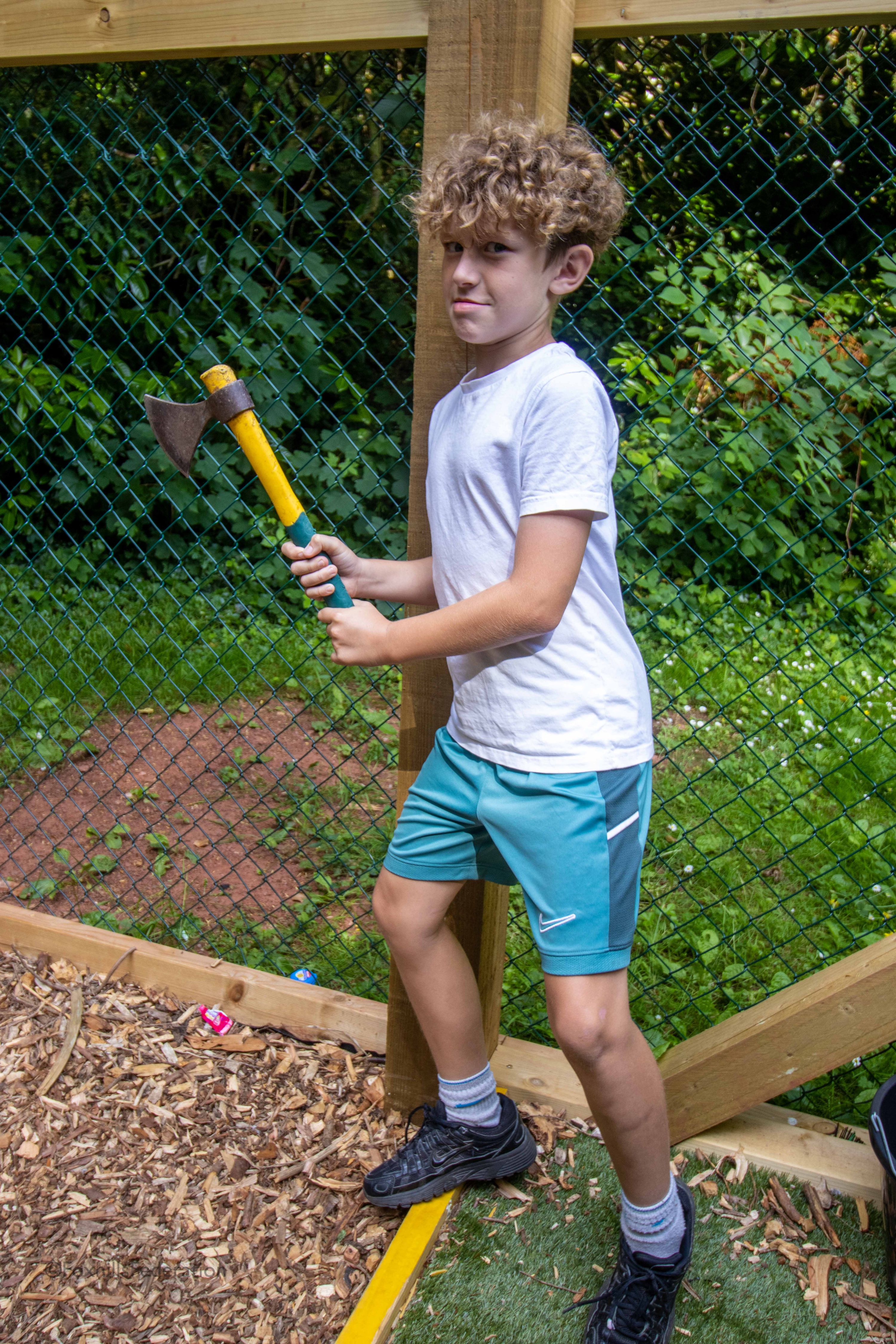 A boy threatens the cameraman with an axe