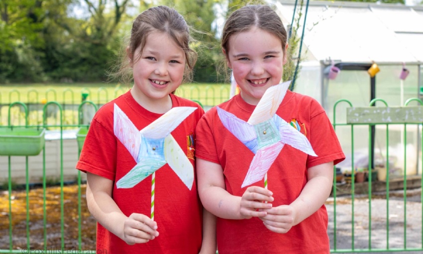 Two girls proudly hold the pinwheels they have created